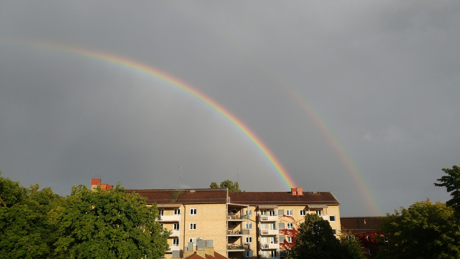 Double arc-en-ciel au-dessus des bâtiments résidentiels après la pluie