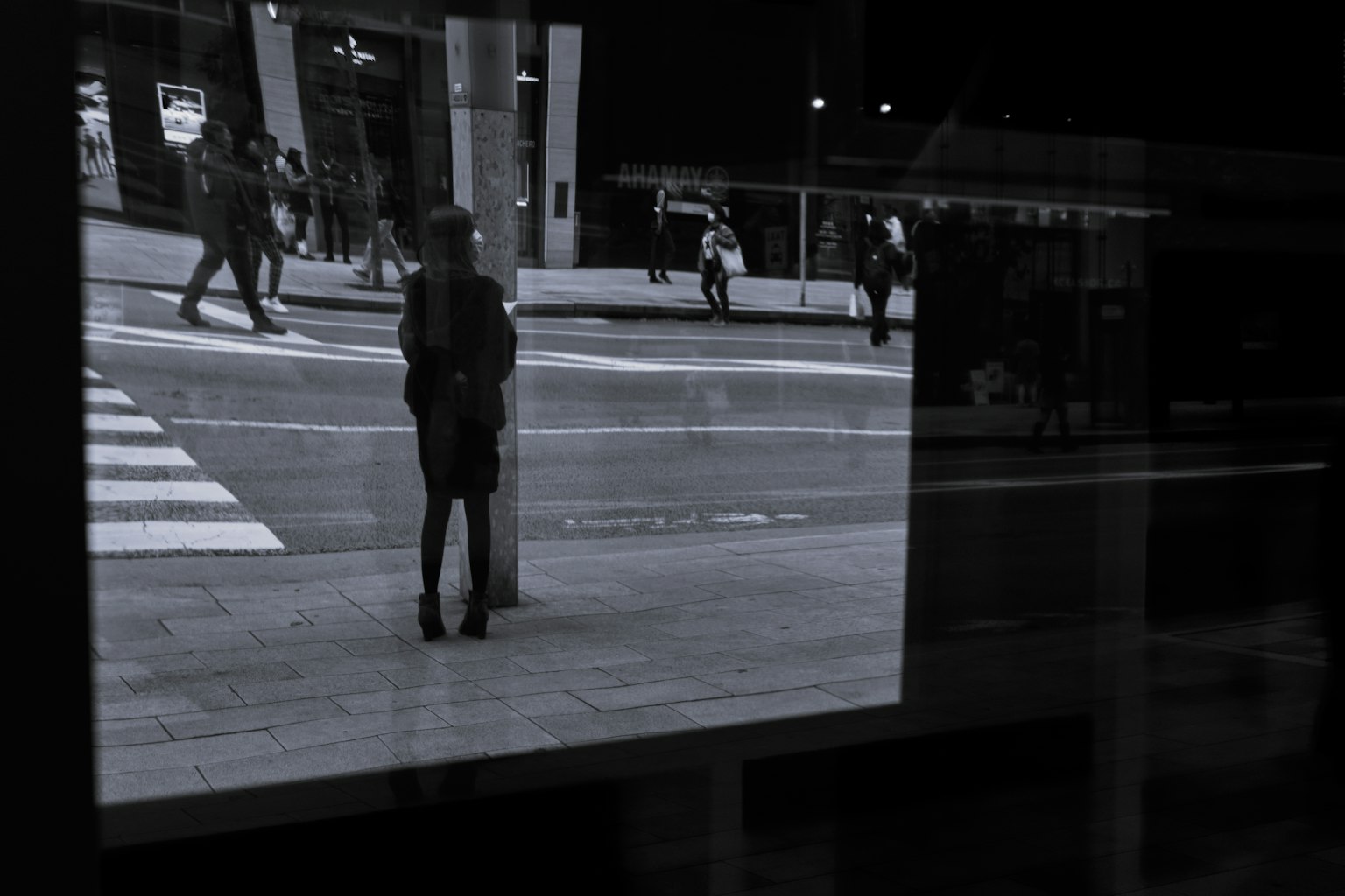 Silhouette di una persona in piedi a un angolo di strada con scena cittadina riflessa
