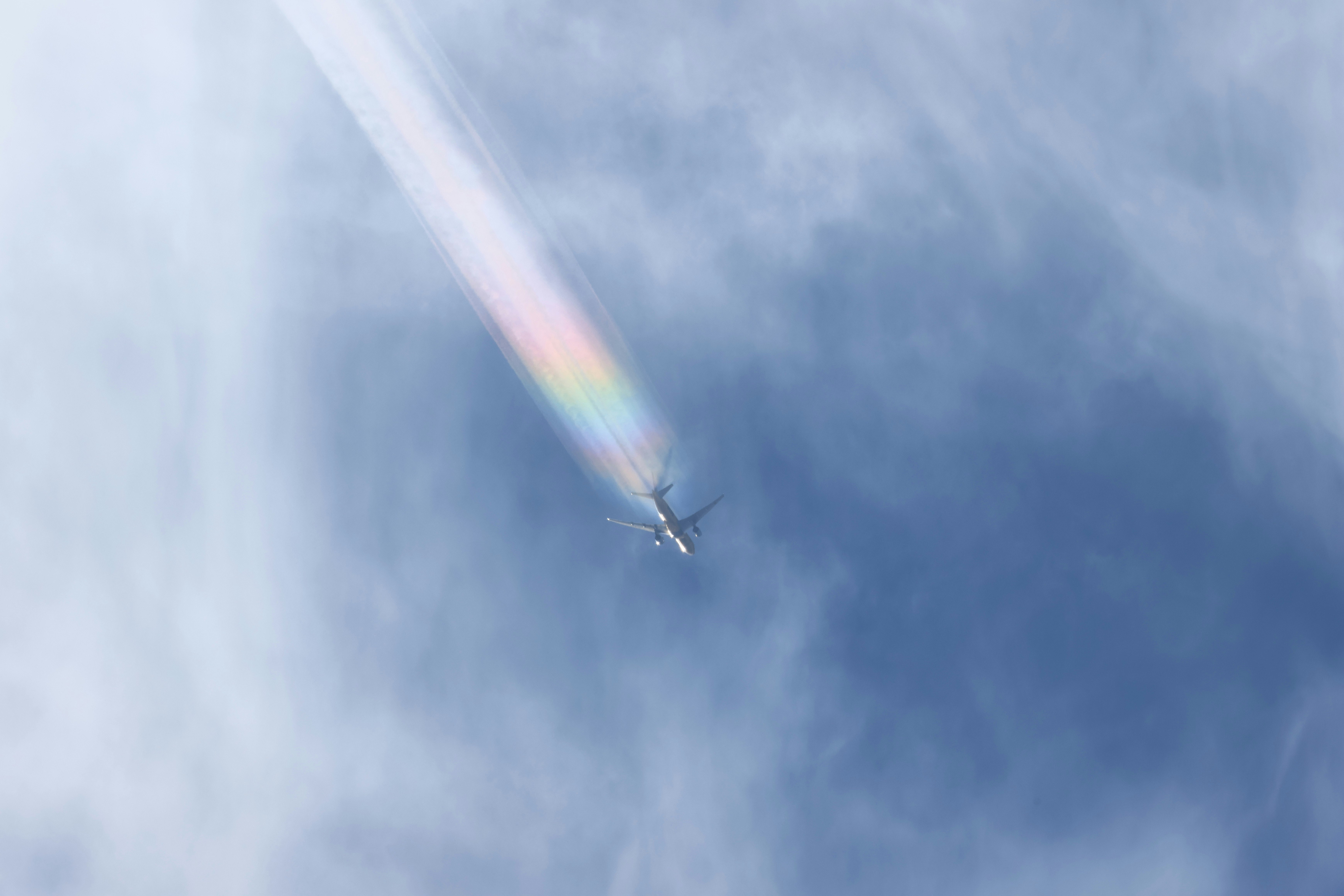 虹のかかる空を飛ぶ飛行機