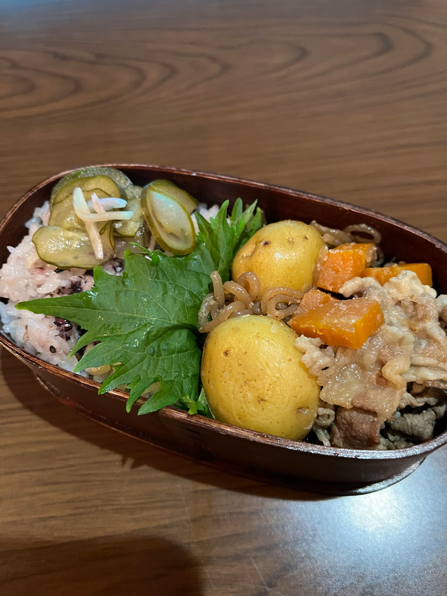 Kotak bento yang berisi nasi, kentang kecil, dan sayuran segar