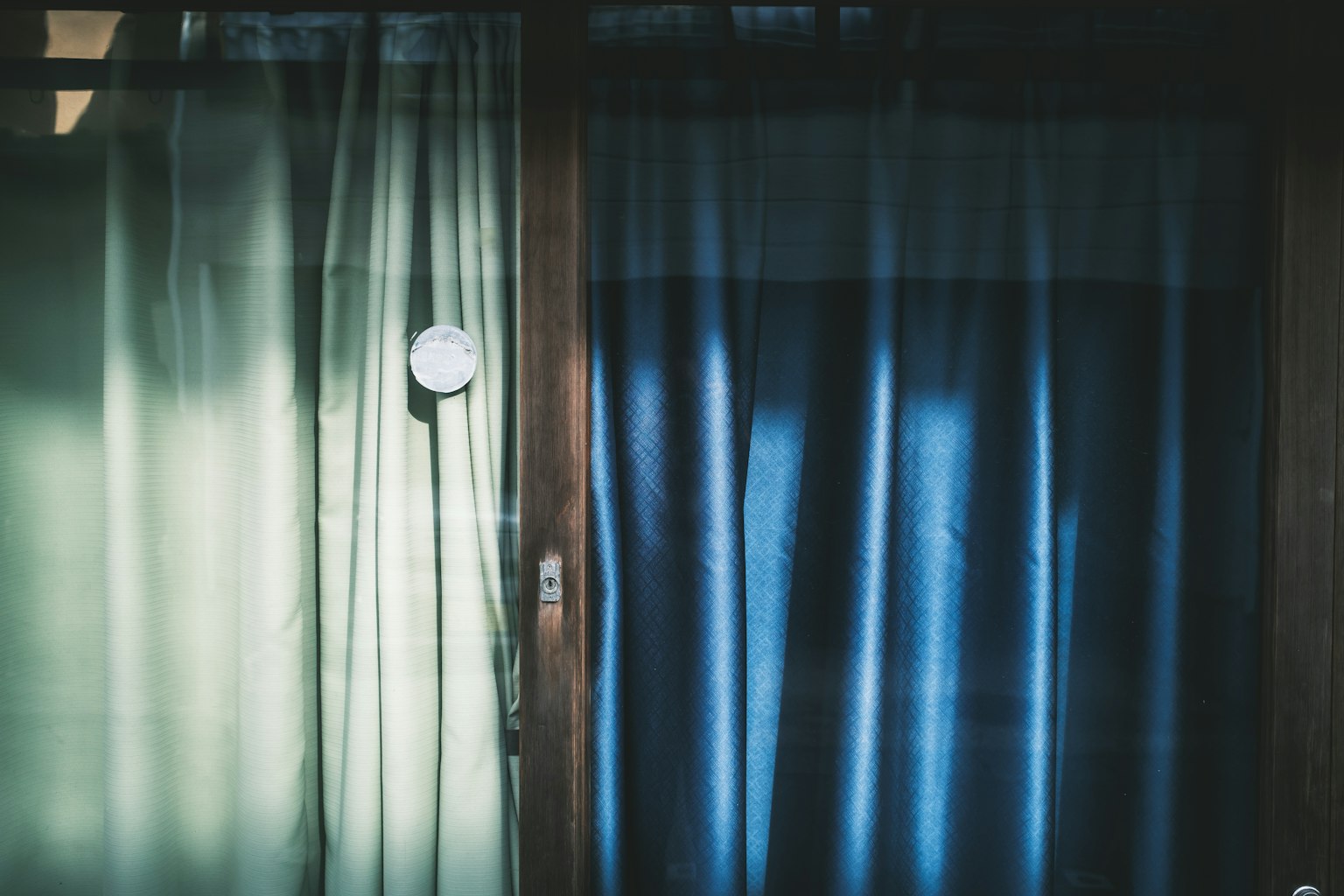 Un interior tranquilo con cortinas verdes y azules cerca de una ventana