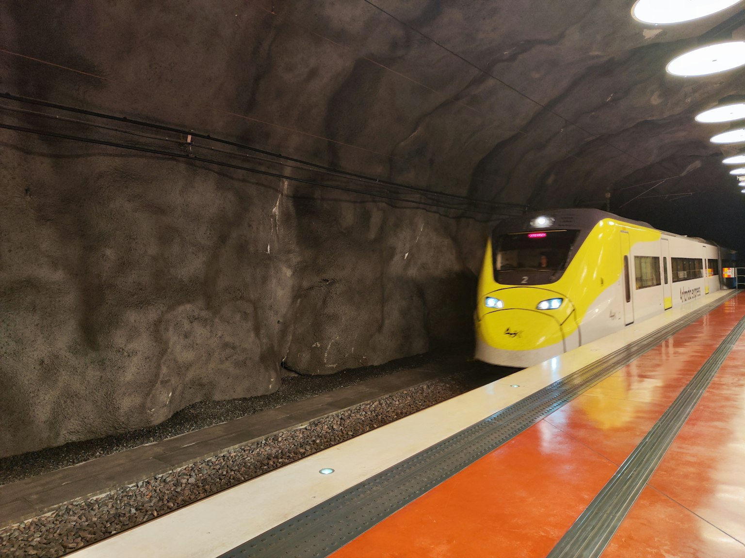 Gelber Zug, der in einem Tunnel mit Felswänden hält