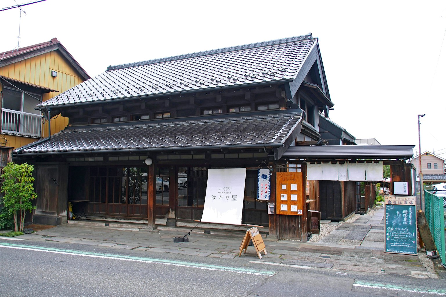 Eksterior rumah tradisional Jepang dengan atap genteng struktur kayu dan pepohonan