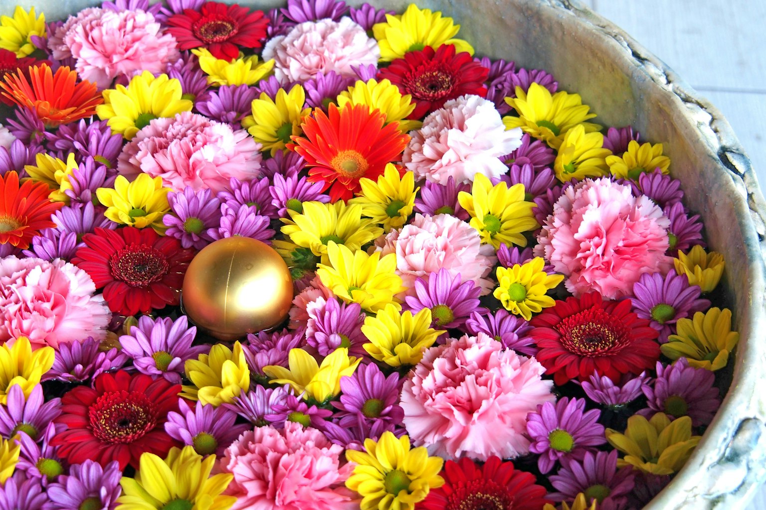 Fiori colorati che galleggiano in una ciotola con una sfera dorata