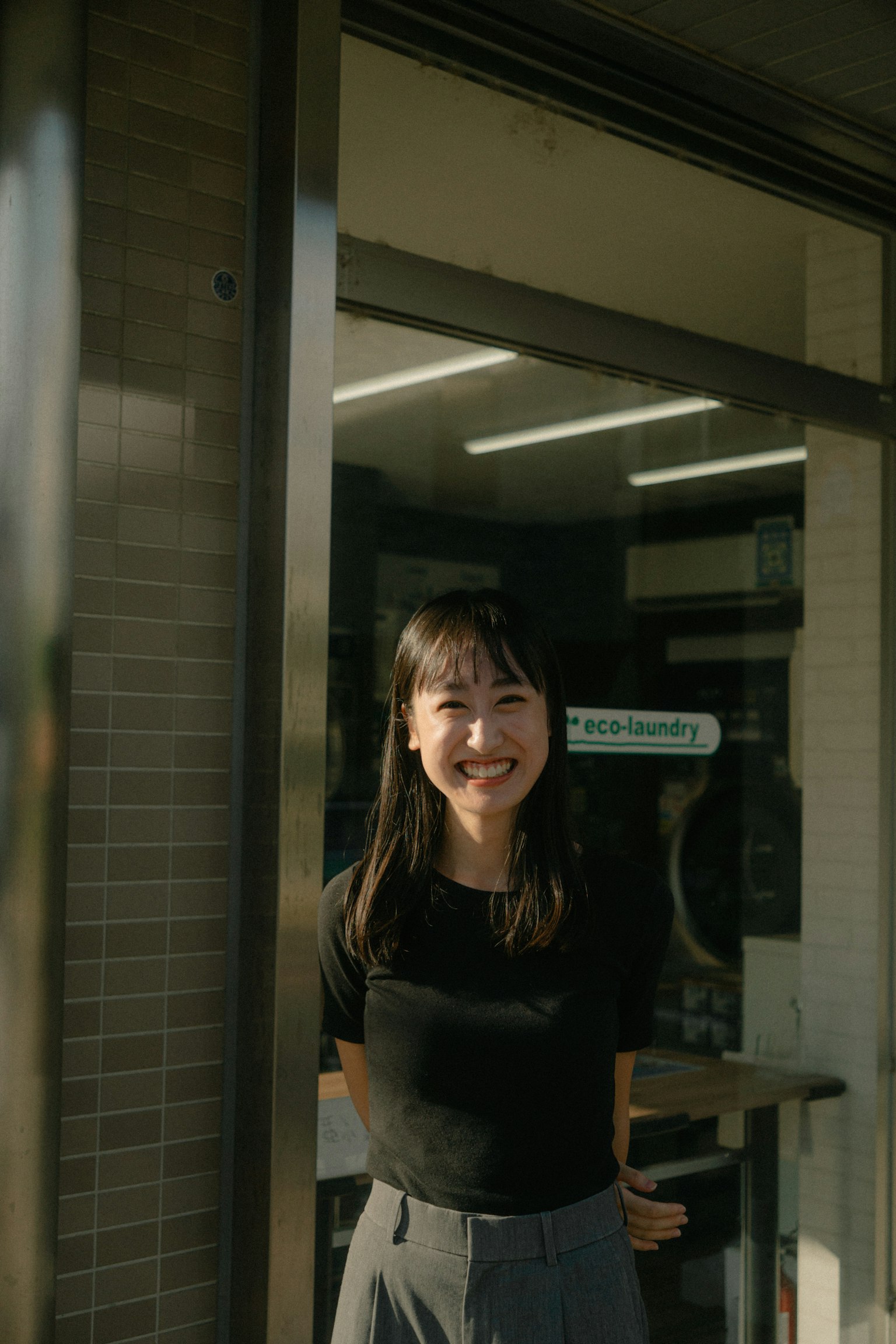 Femme souriante en haut noir se tenant devant une porte