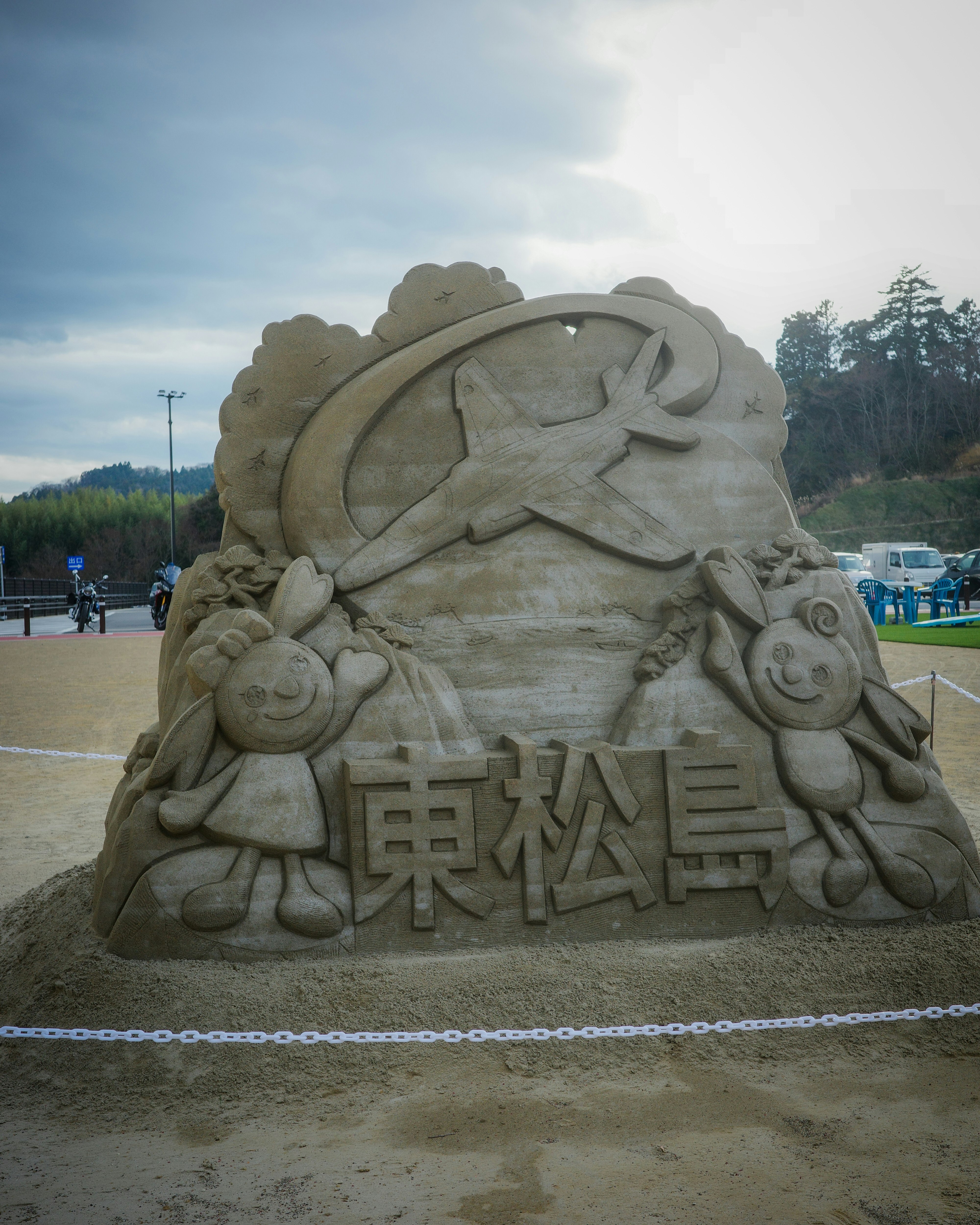 砂像の「栗松島」文字とキャラクターの彫刻がある広場