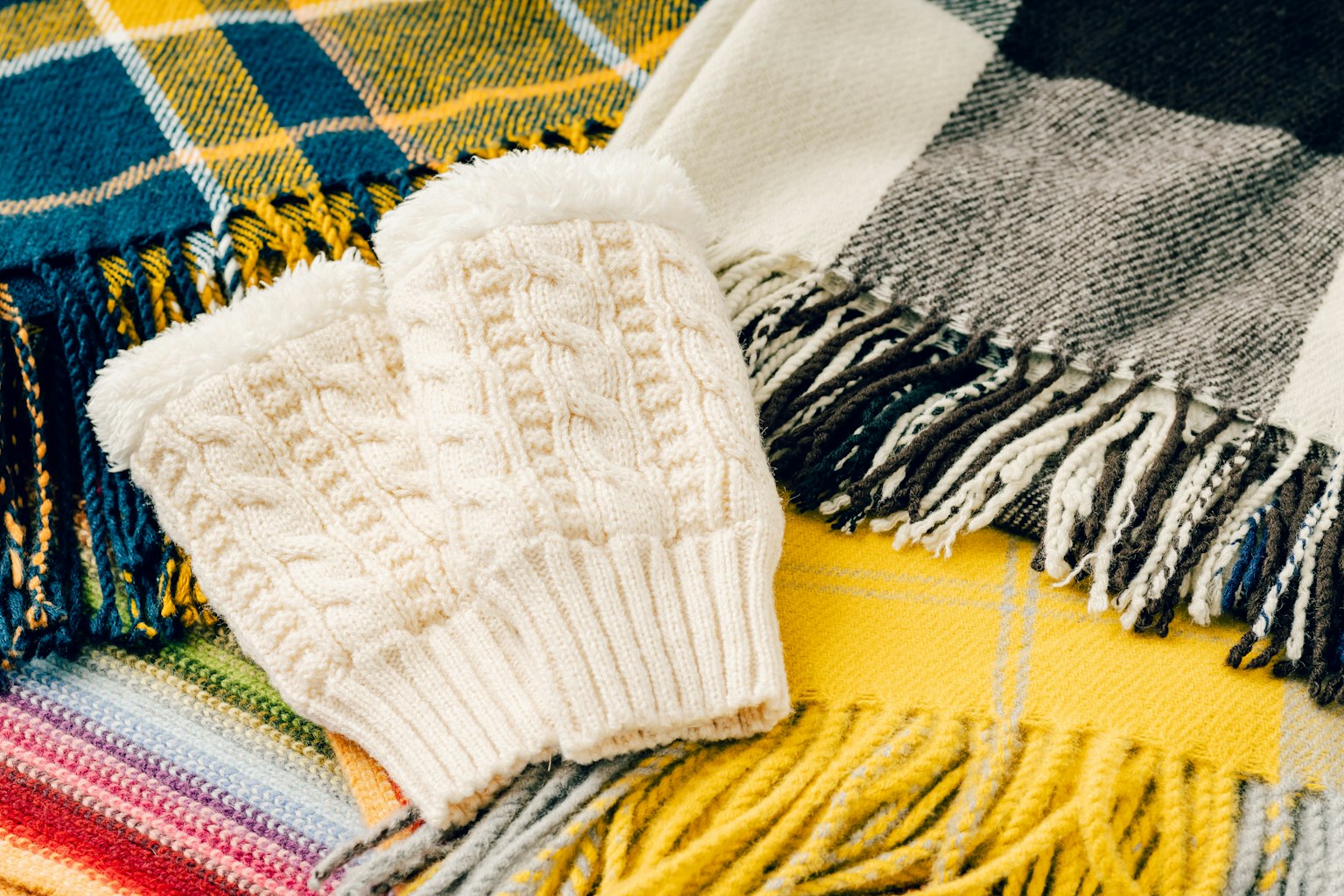 Paar weißer Handschuhe auf bunten Decken