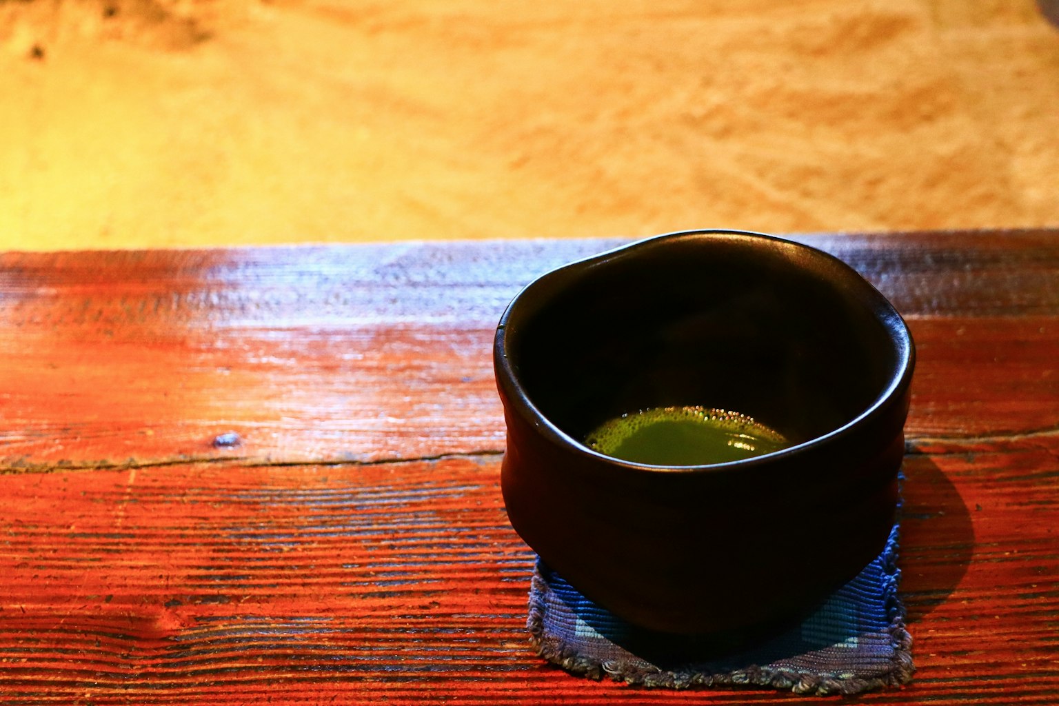 Mangkuk hitam dengan matcha di atas meja kayu