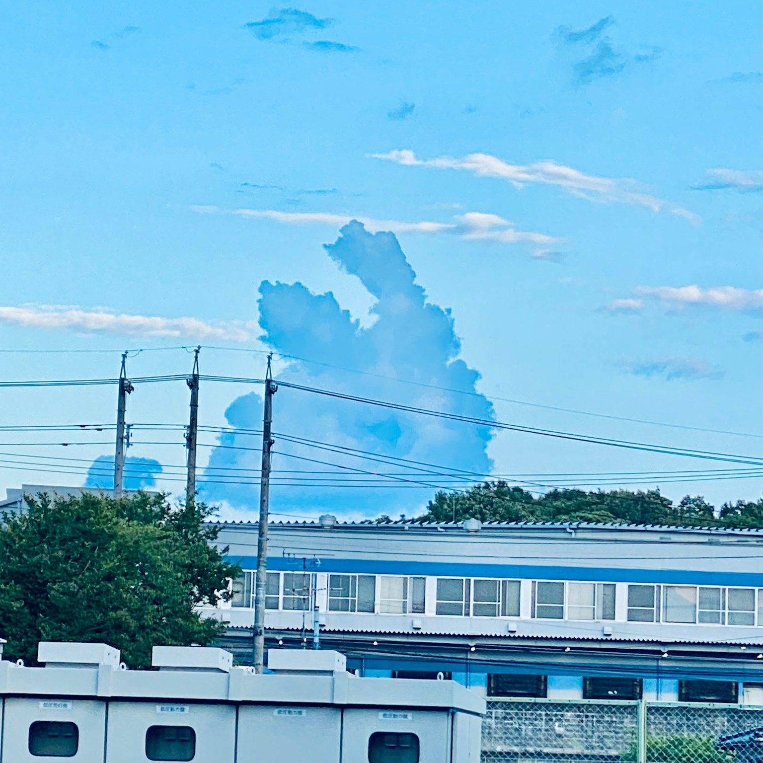 Formasi awan unik di langit biru dengan bangunan di bawah