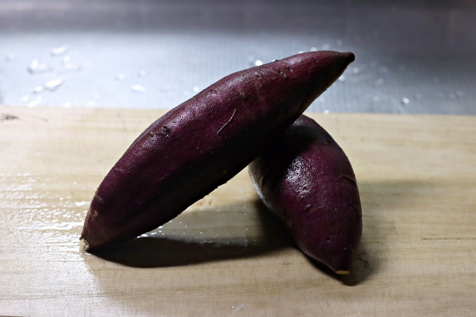 Zwei violette Süßkartoffeln auf einer Holzoberfläche