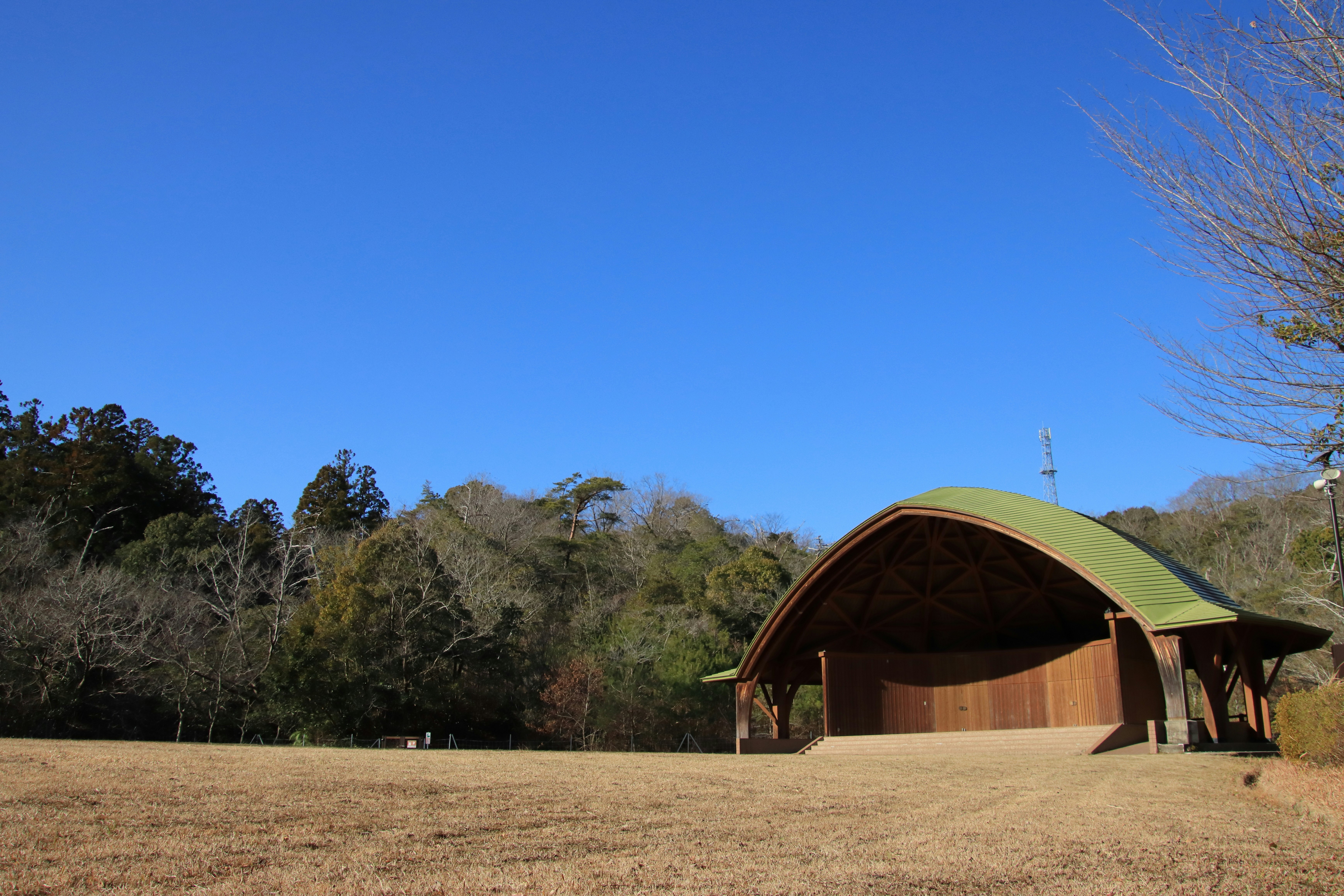 wooden shelter on a grassy field under a clear blue sky