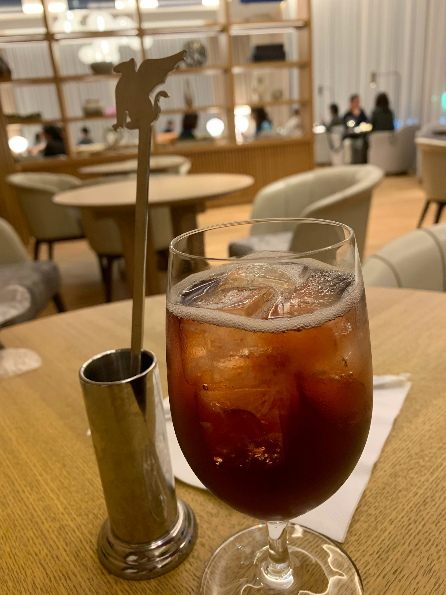 Una scena di bar elegante con una bevanda ghiacciata e un mescolatore unico su un tavolo di legno