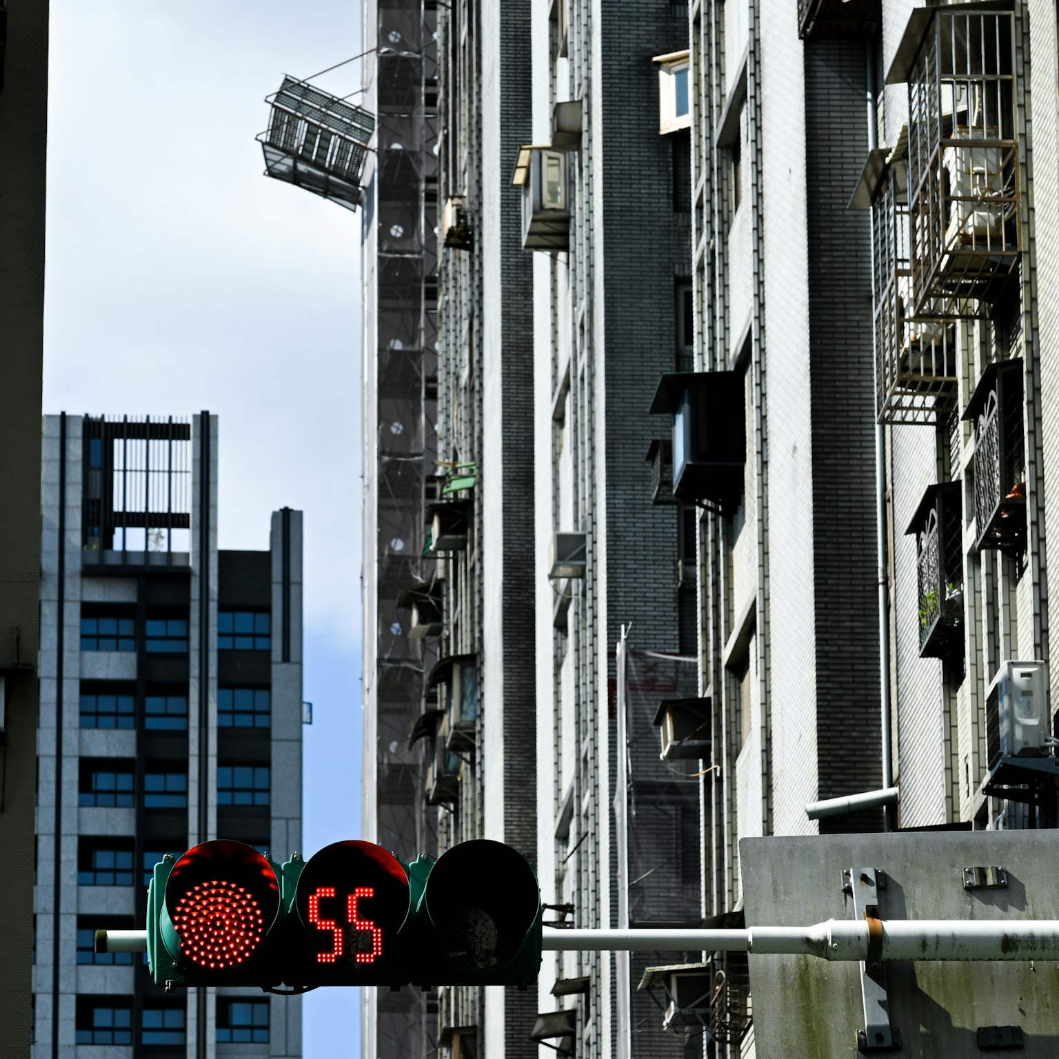 Urban scene featuring a traffic light displaying a red signal and the number 55