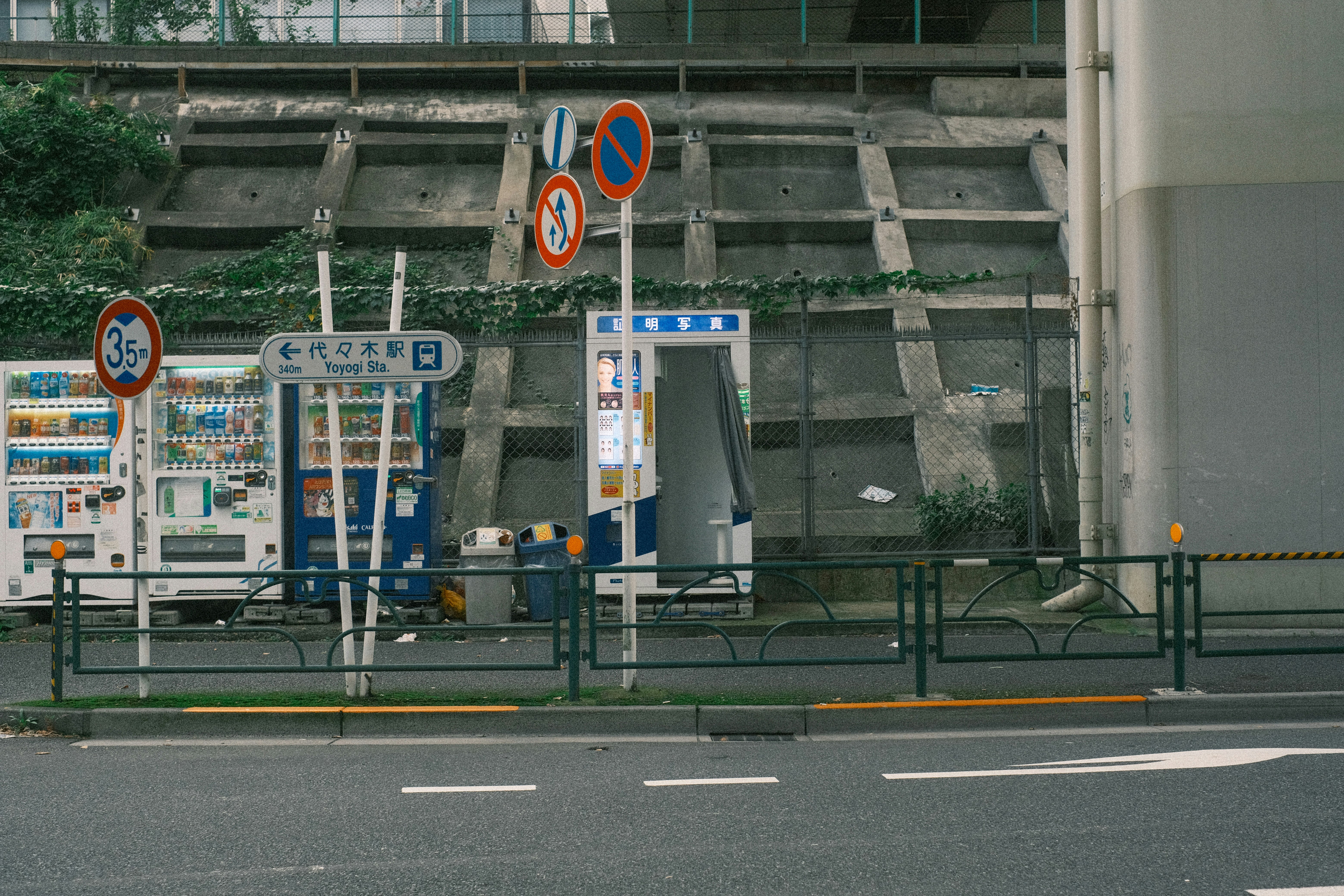 高架下のバス停風の標識と交通案内板のある道路風景