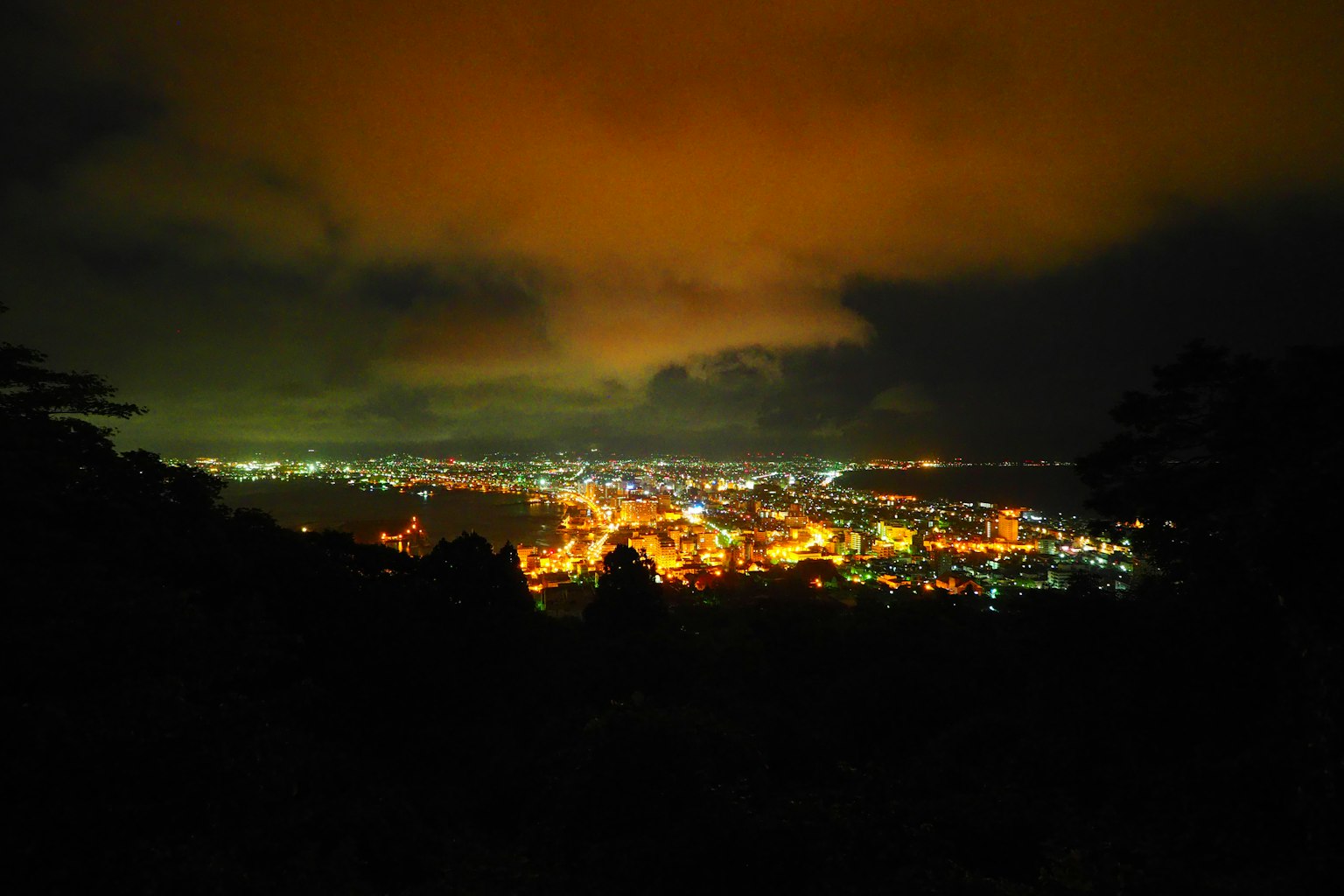 Pemandangan malam kota dengan awan oranye dan lampu kota yang terang