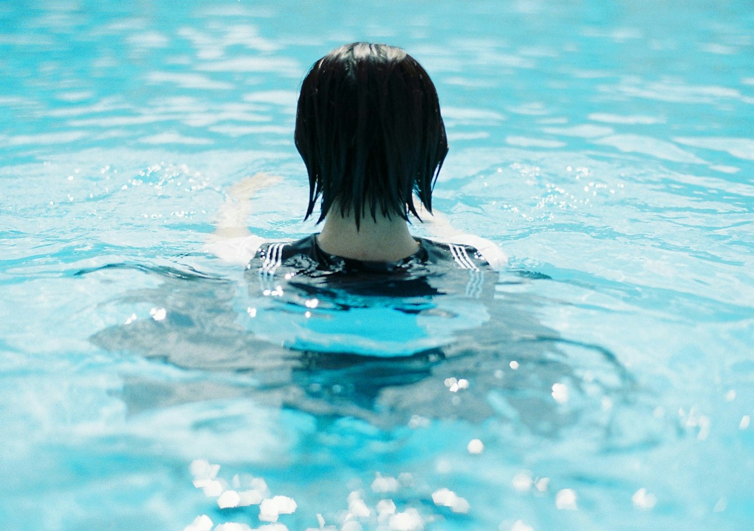 一个黑发的人背对着浮在泳池里