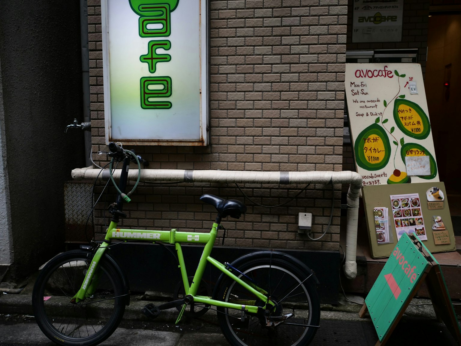 Un vélo vert à côté d'un panneau de café dans un environnement urbain