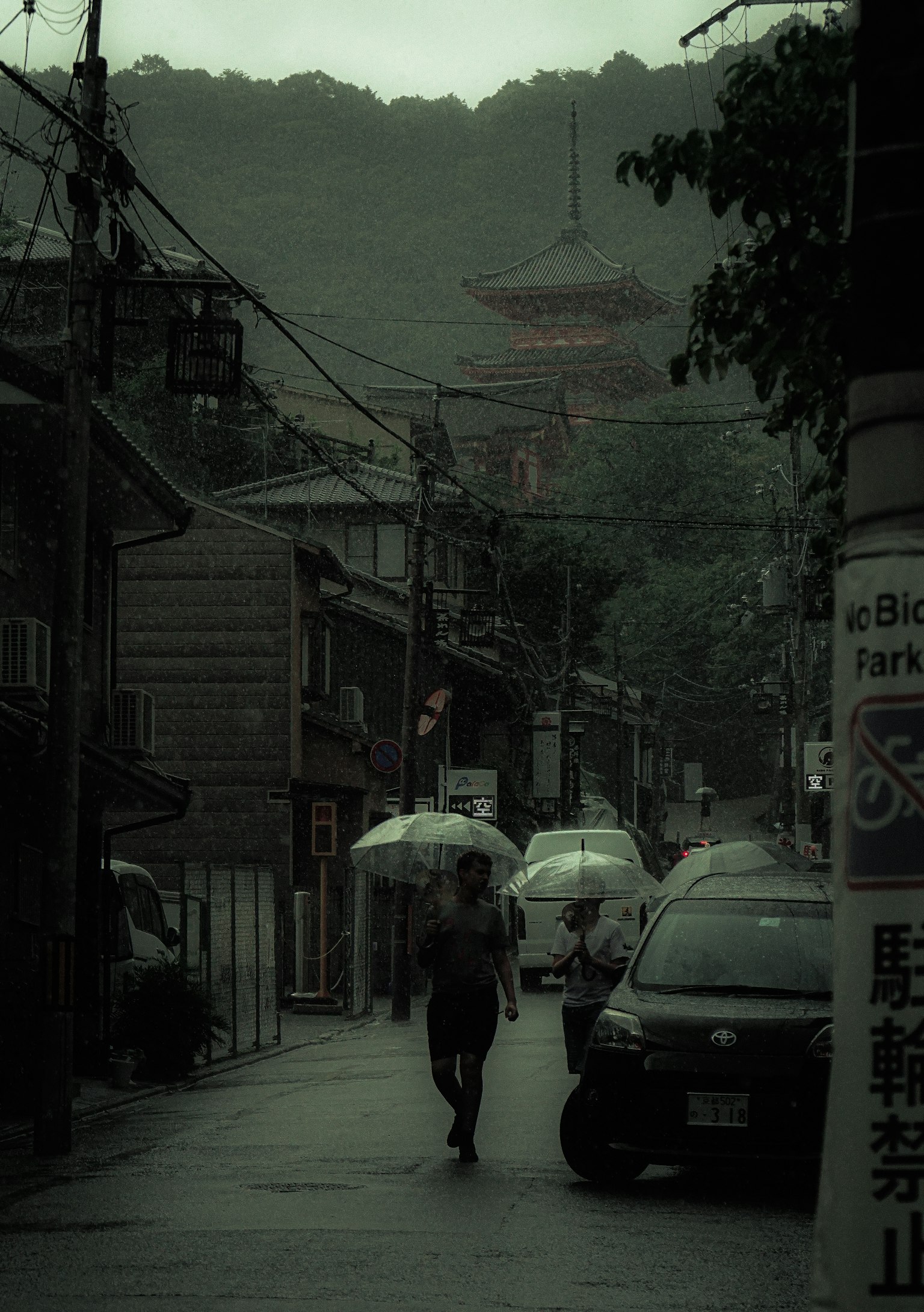 在霧氣瀰漫的街道上，一個人拿著傘走在老舊建築之間