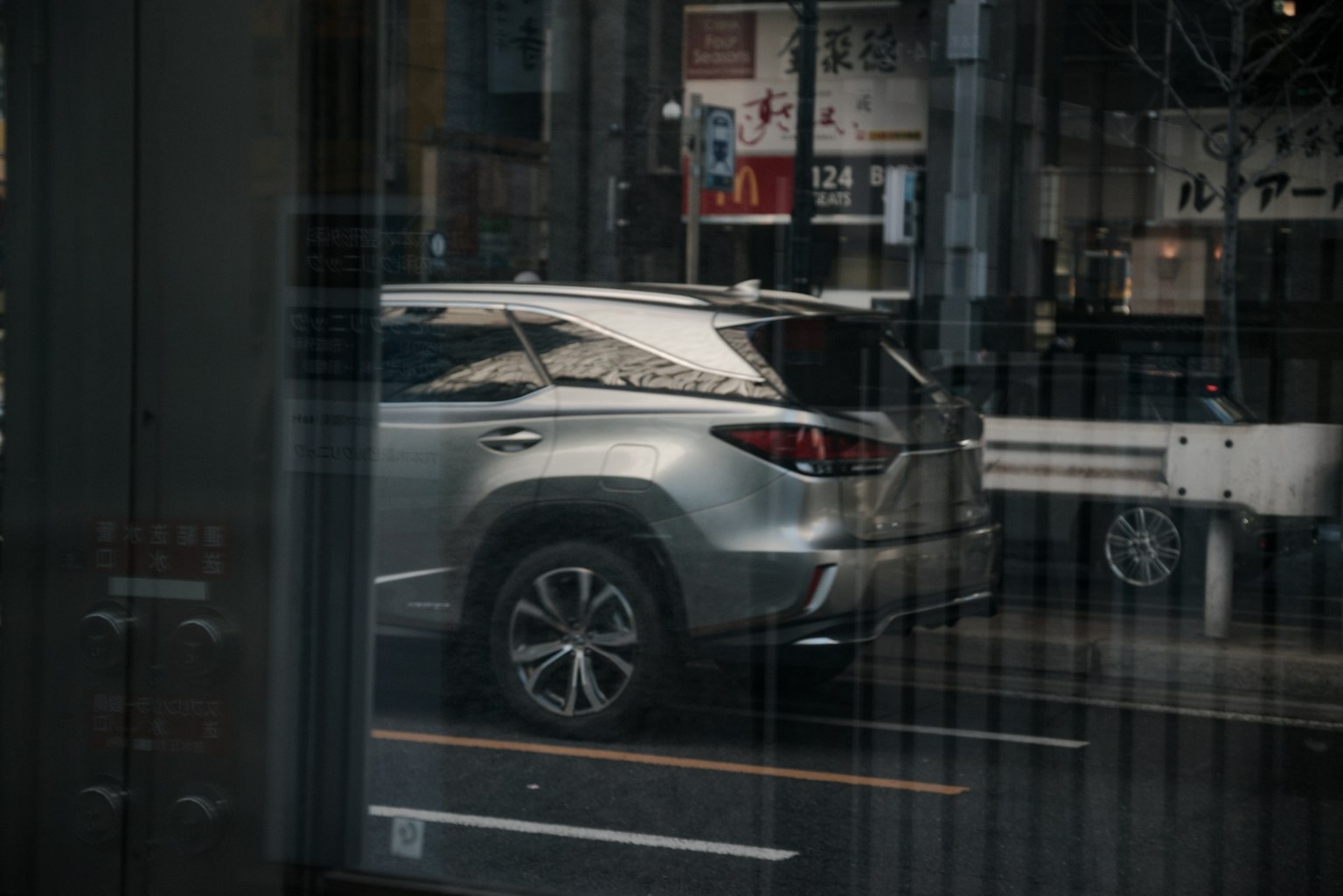 SUV argenté vu à travers une fenêtre avec un arrière-plan urbain