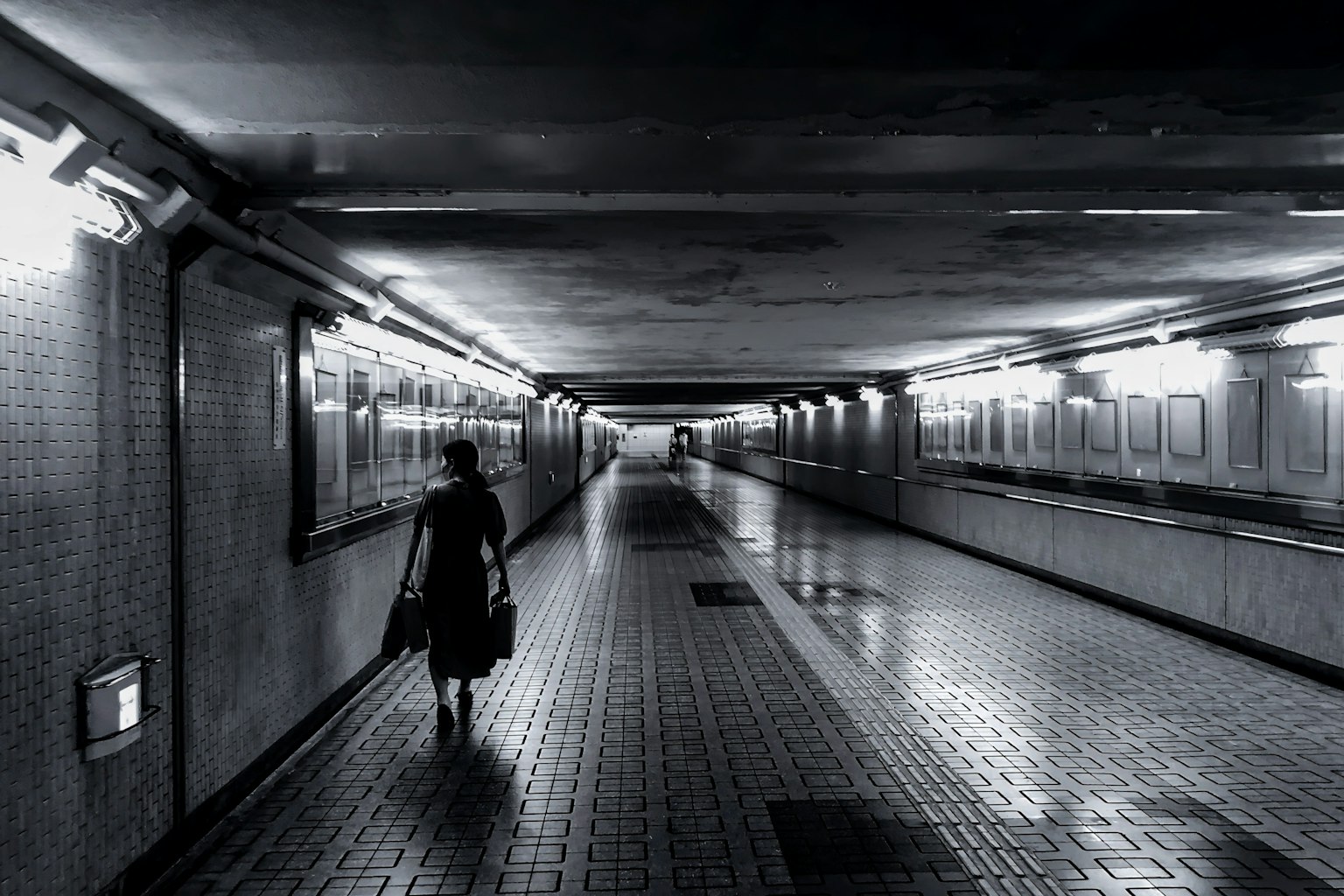 暗い地下道を歩く人影と明るい照明