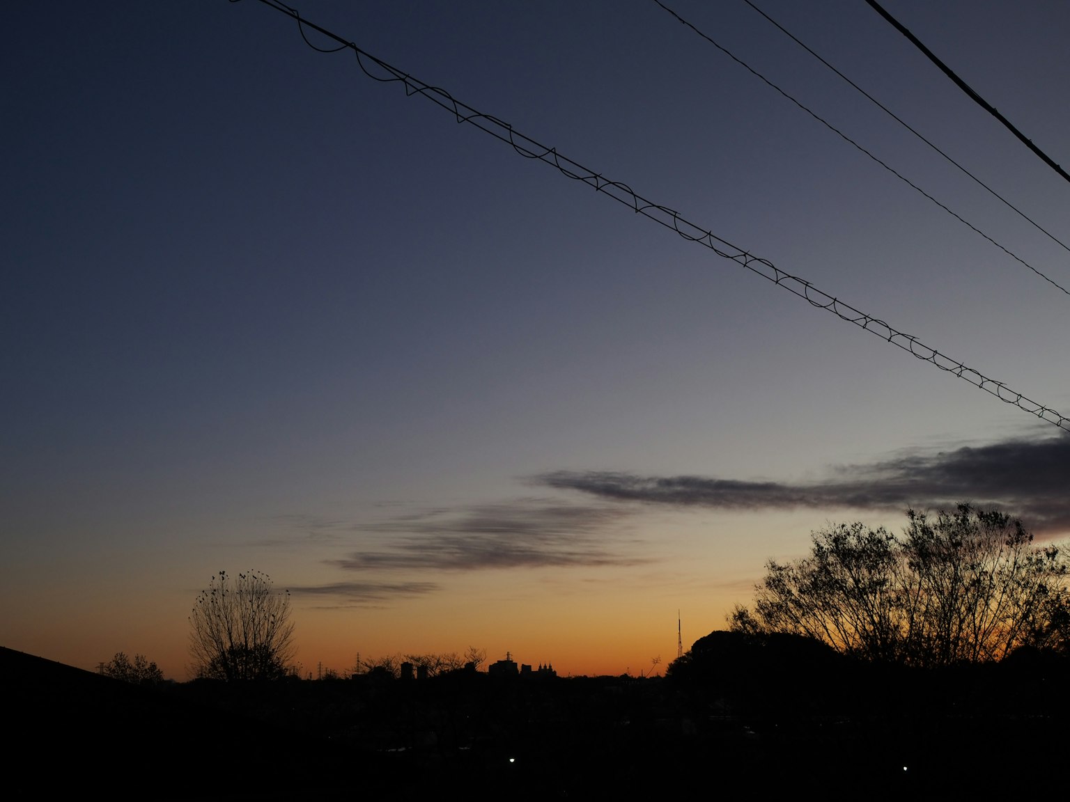 Un cielo al tramonto con linee elettriche silhouette all'orizzonte