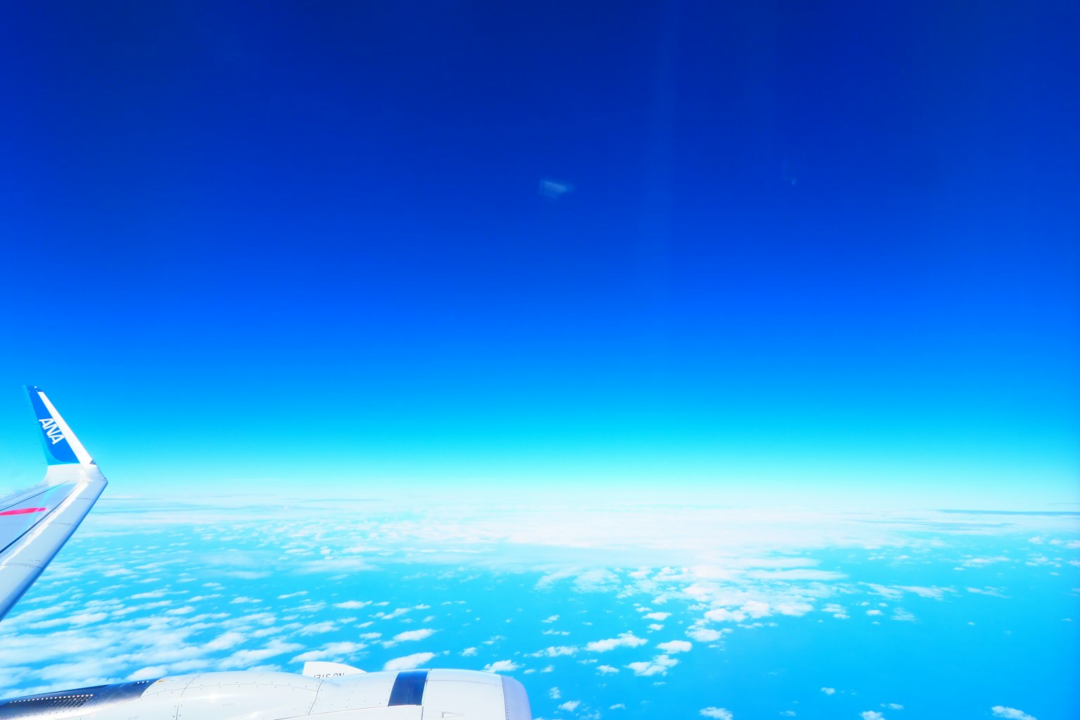 View from an airplane wing showing blue sky and clouds
