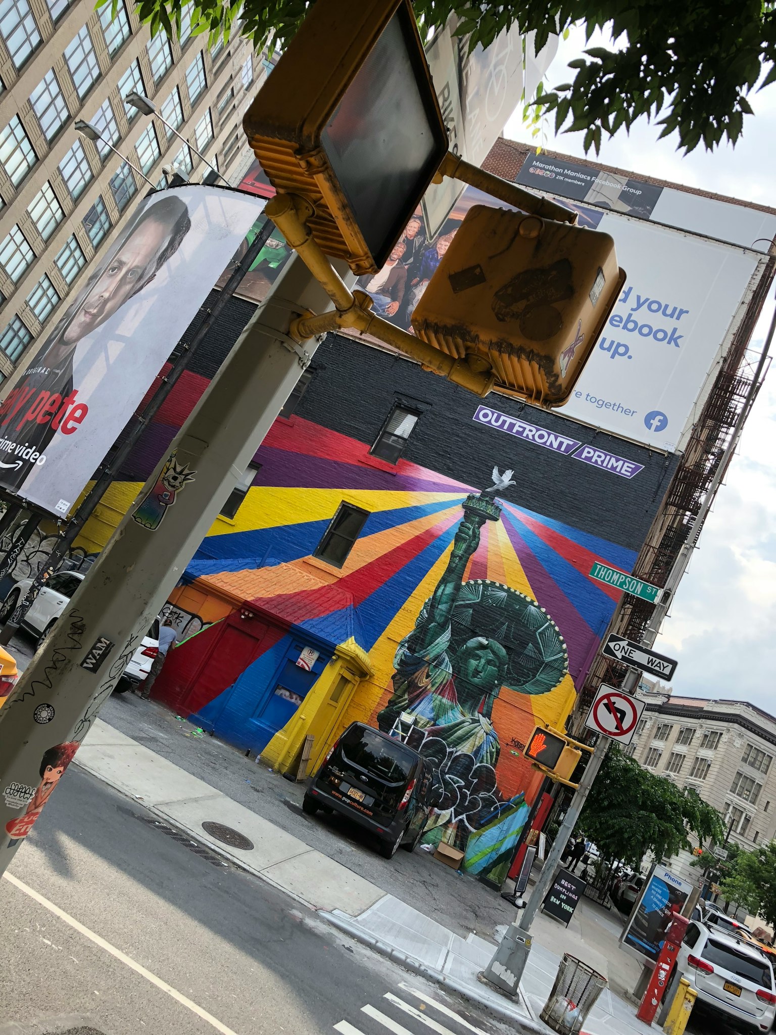 Mural berwarna dengan Patung Liberty di sudut kota dengan lampu lalu lintas