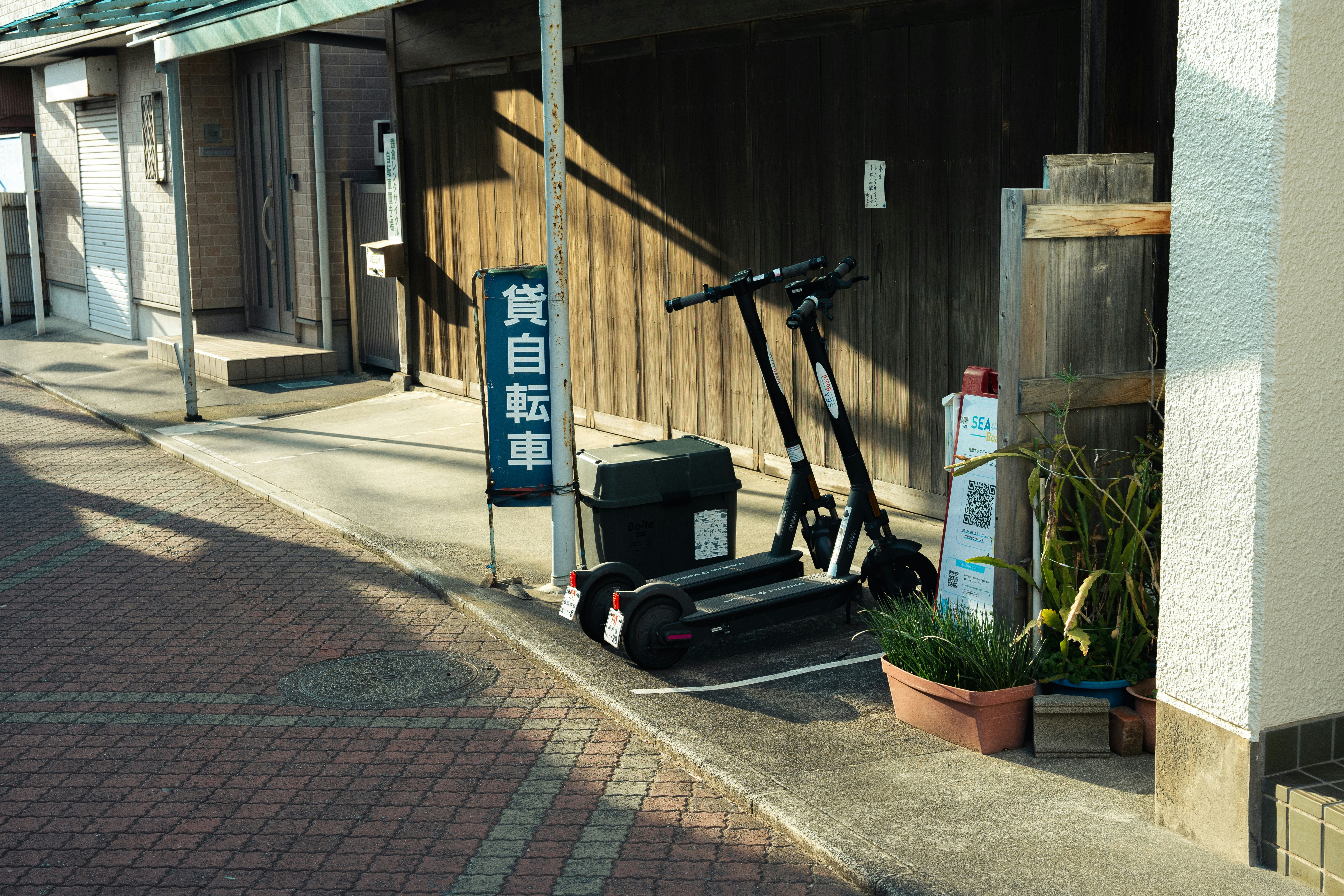electric kick scooter and bicycle lined up at a narrow alley storefront