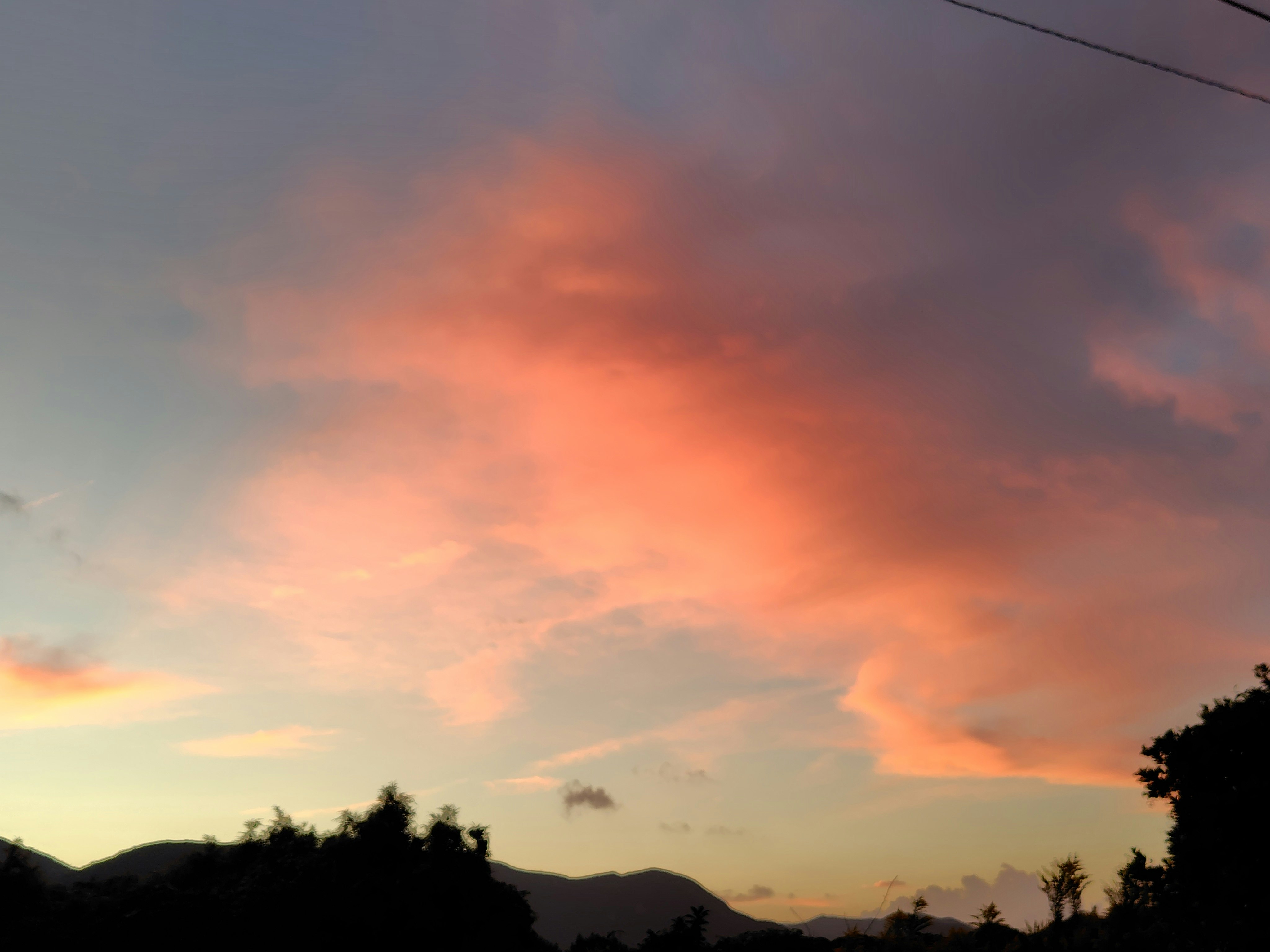awan diterangi cahaya matahari terbit di atas lanskap jauh