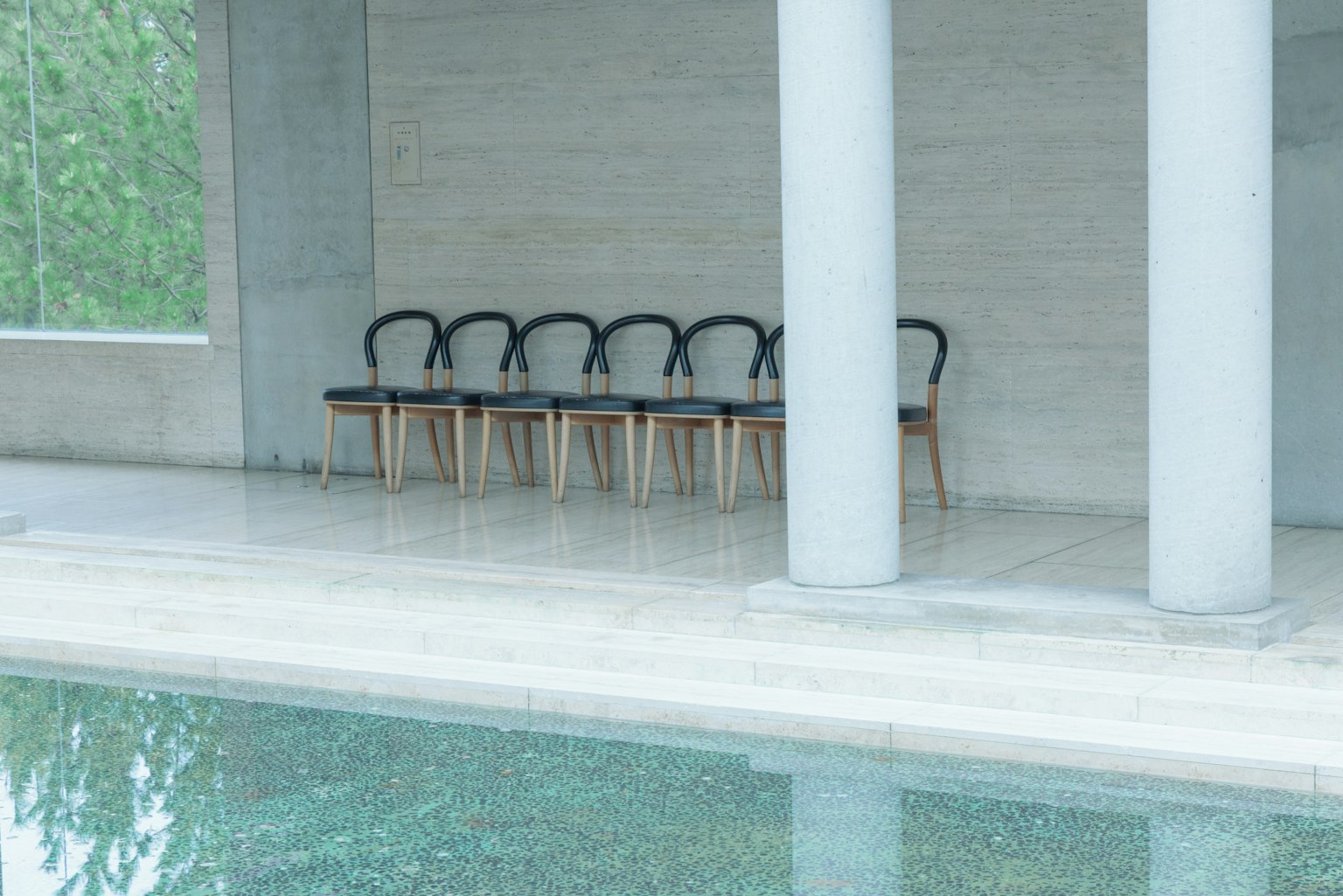 Modernes Interieur mit einer Reihe von Stühlen am Pool und Säulen