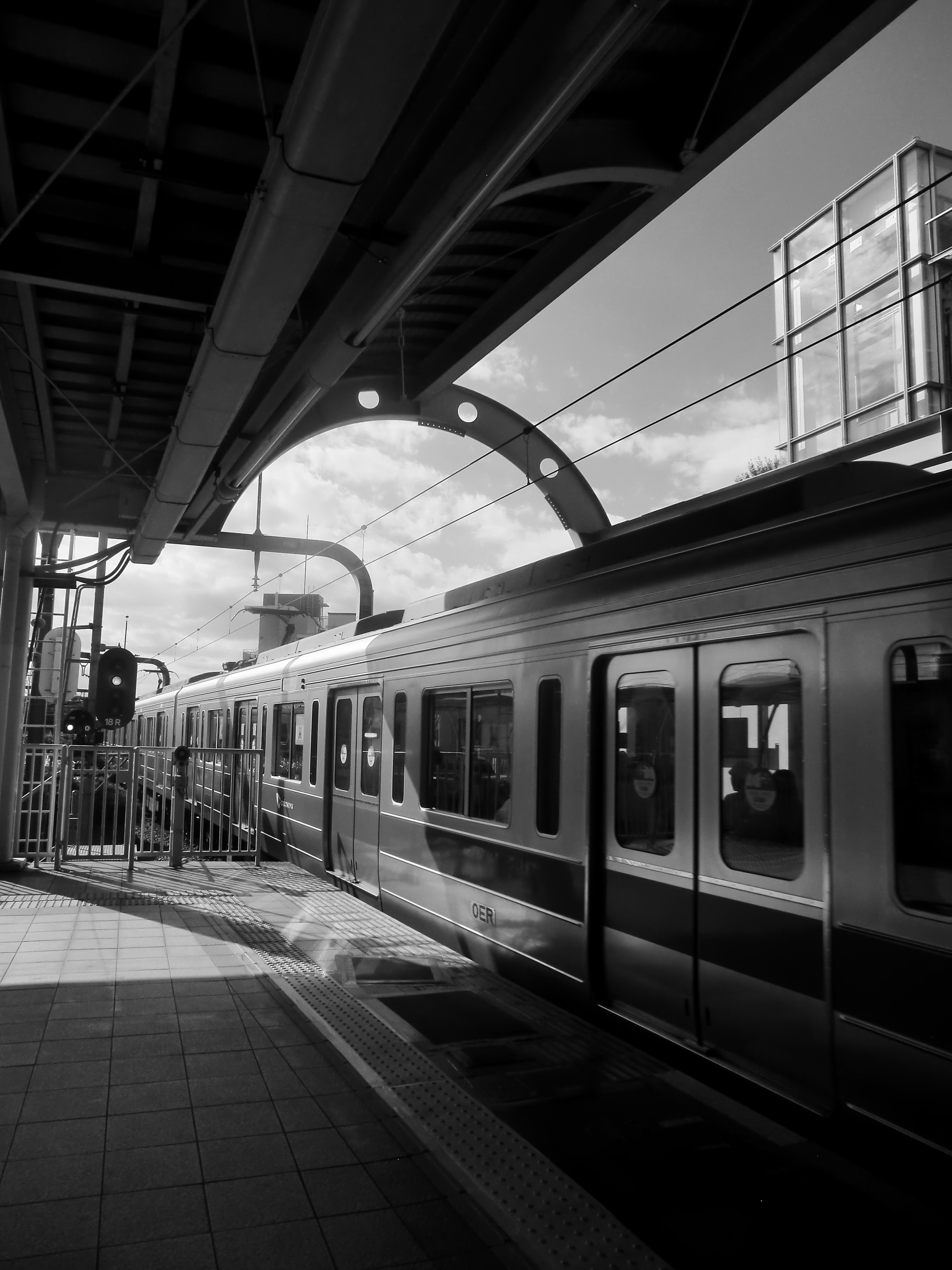 小田急・経堂駅のホームを走る電車のモノクロスナップ