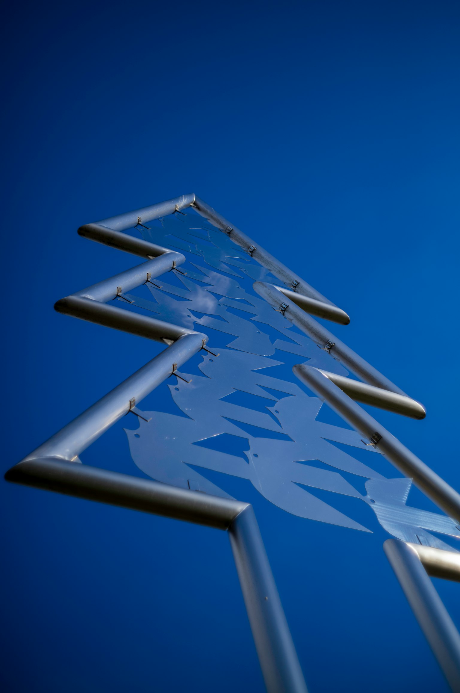 Sculpture en forme de flèche métallique sur fond bleu