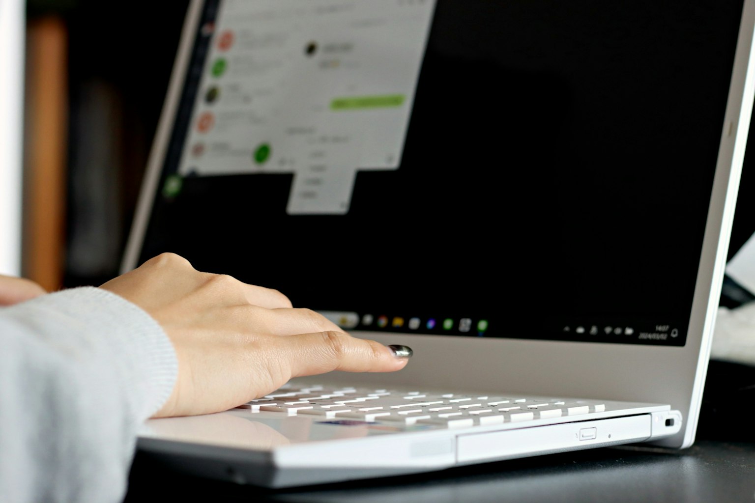 Gros plan d'une main utilisant un ordinateur portable avec un écran sombre affichant une application