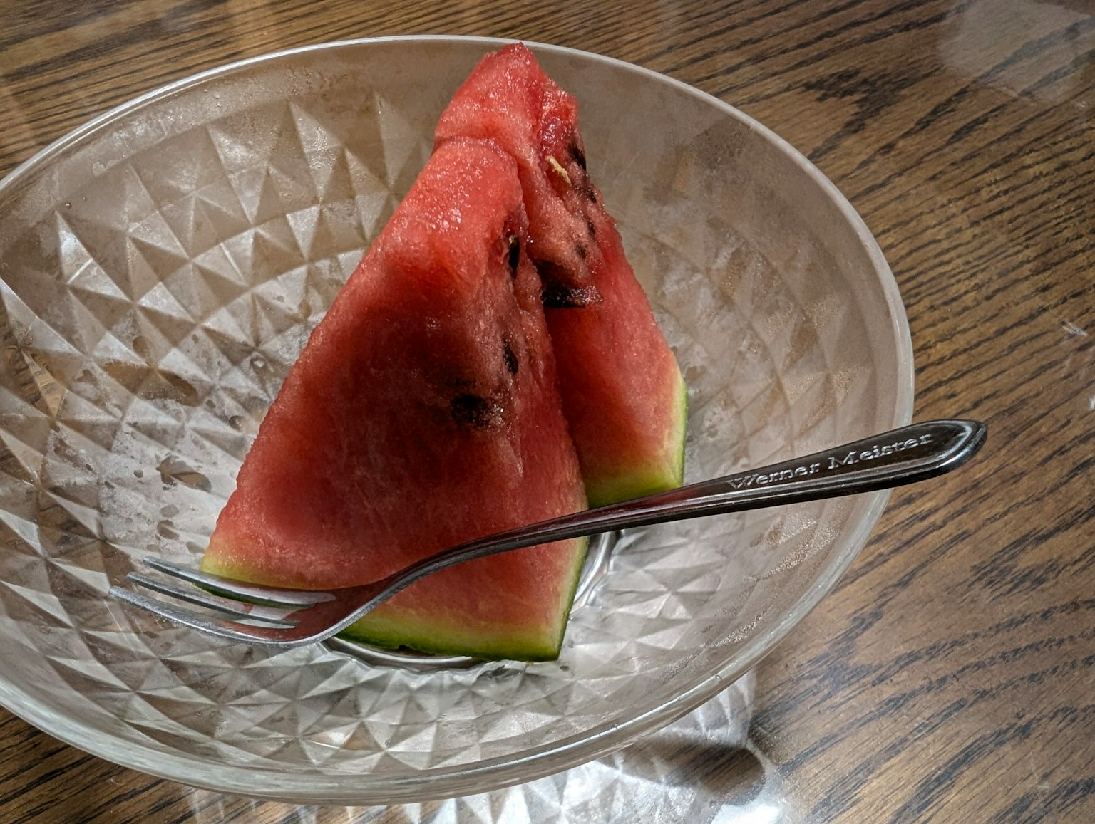 투명한 접시에 담긴 삼각형 수박 조각과 포크