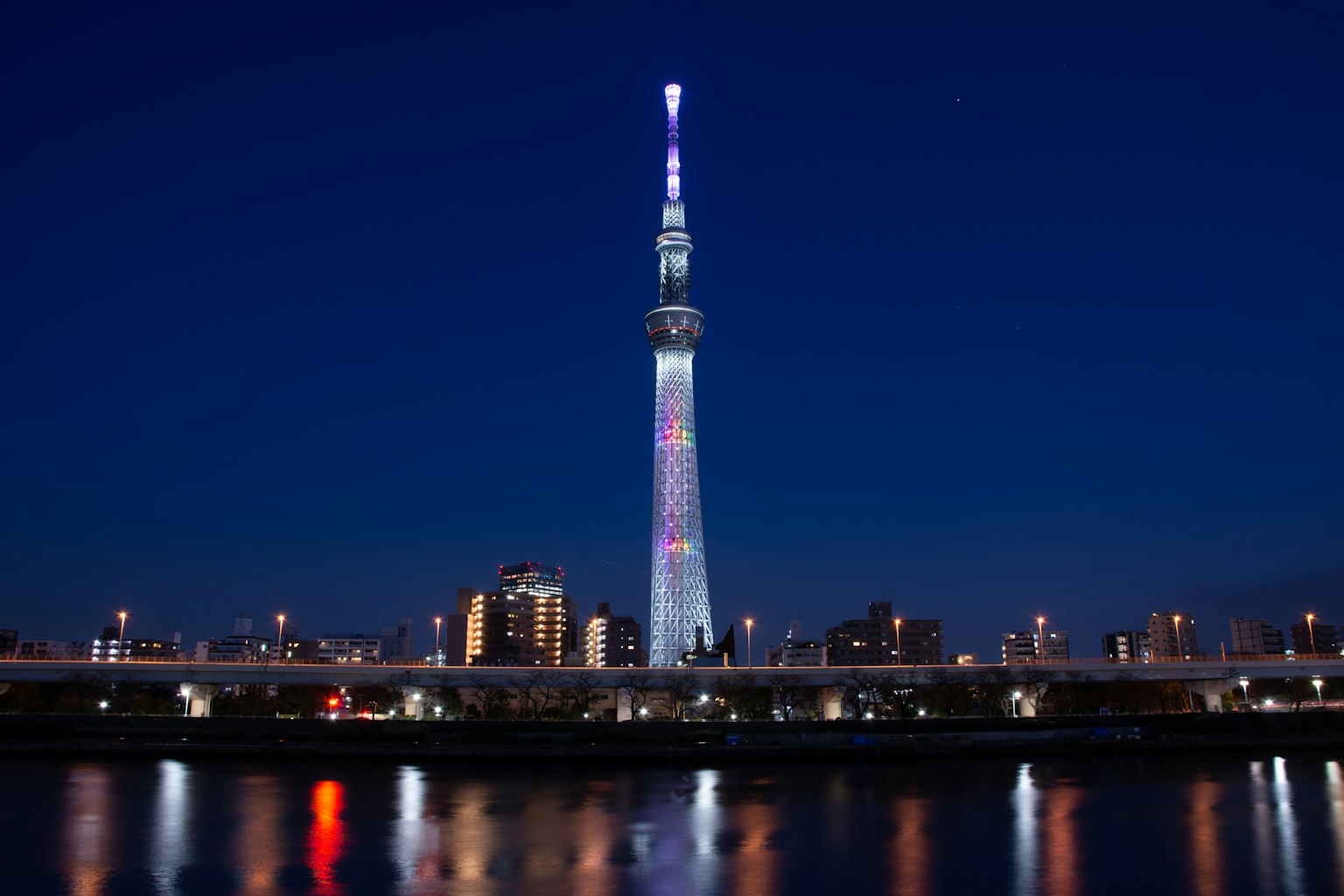 Tokyo Skytree bei Nacht beleuchtet mit Spiegelungen im Fluss