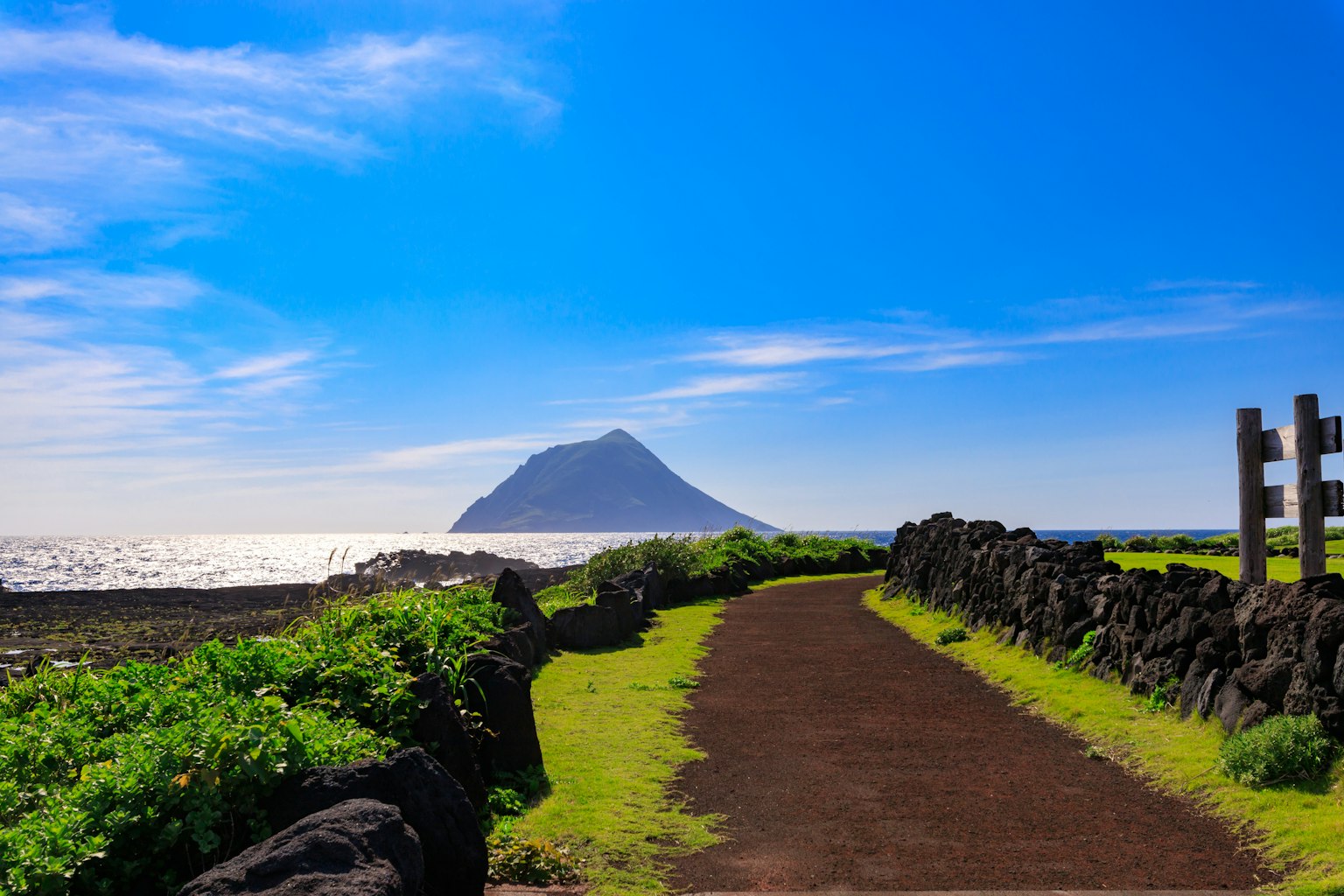Scenic pathway leading to a distant mountain under a clear blue sky