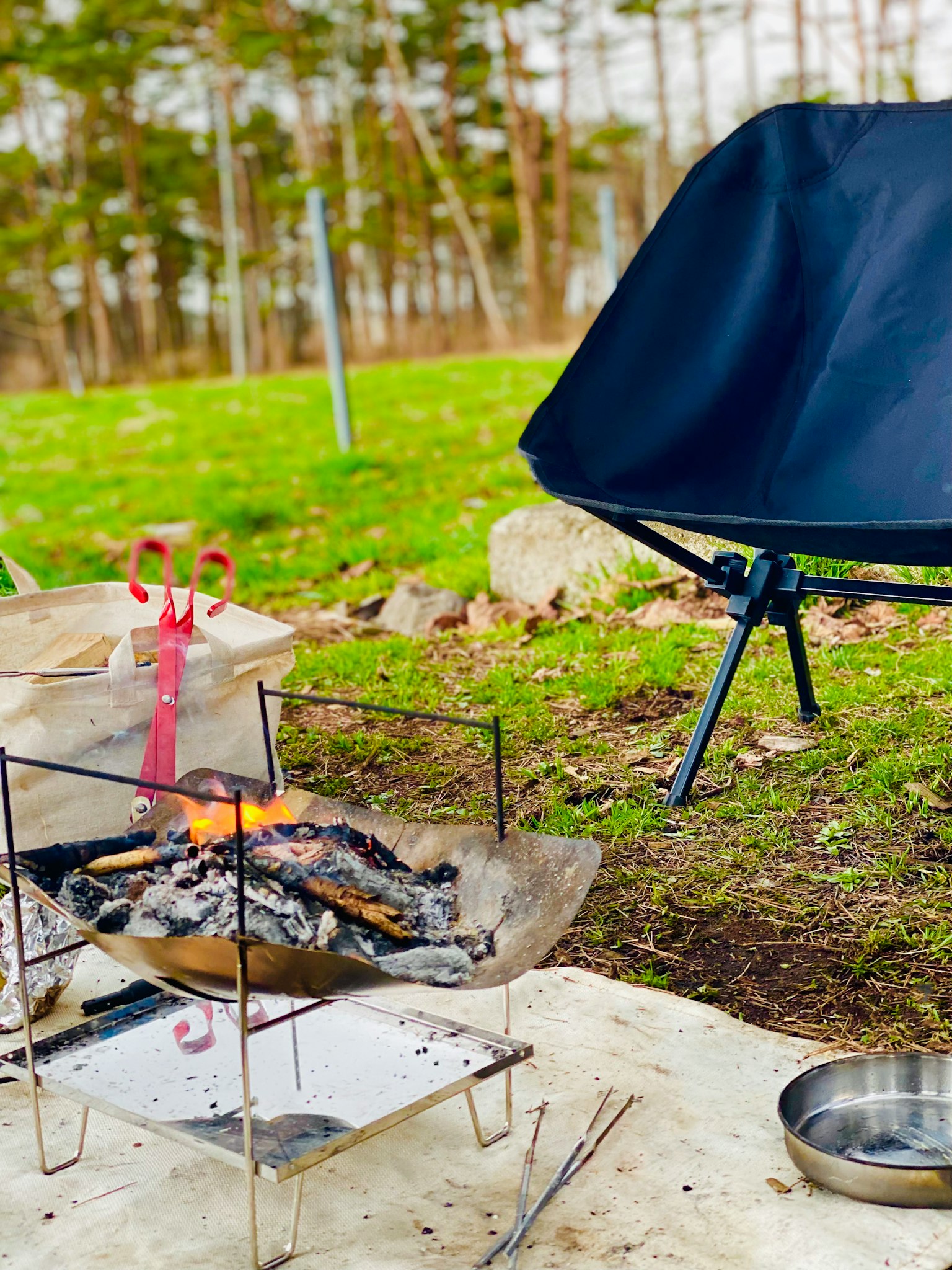 Außenszene mit einem kompakten Stuhl und einem Grill vor einem Lagerfeuer