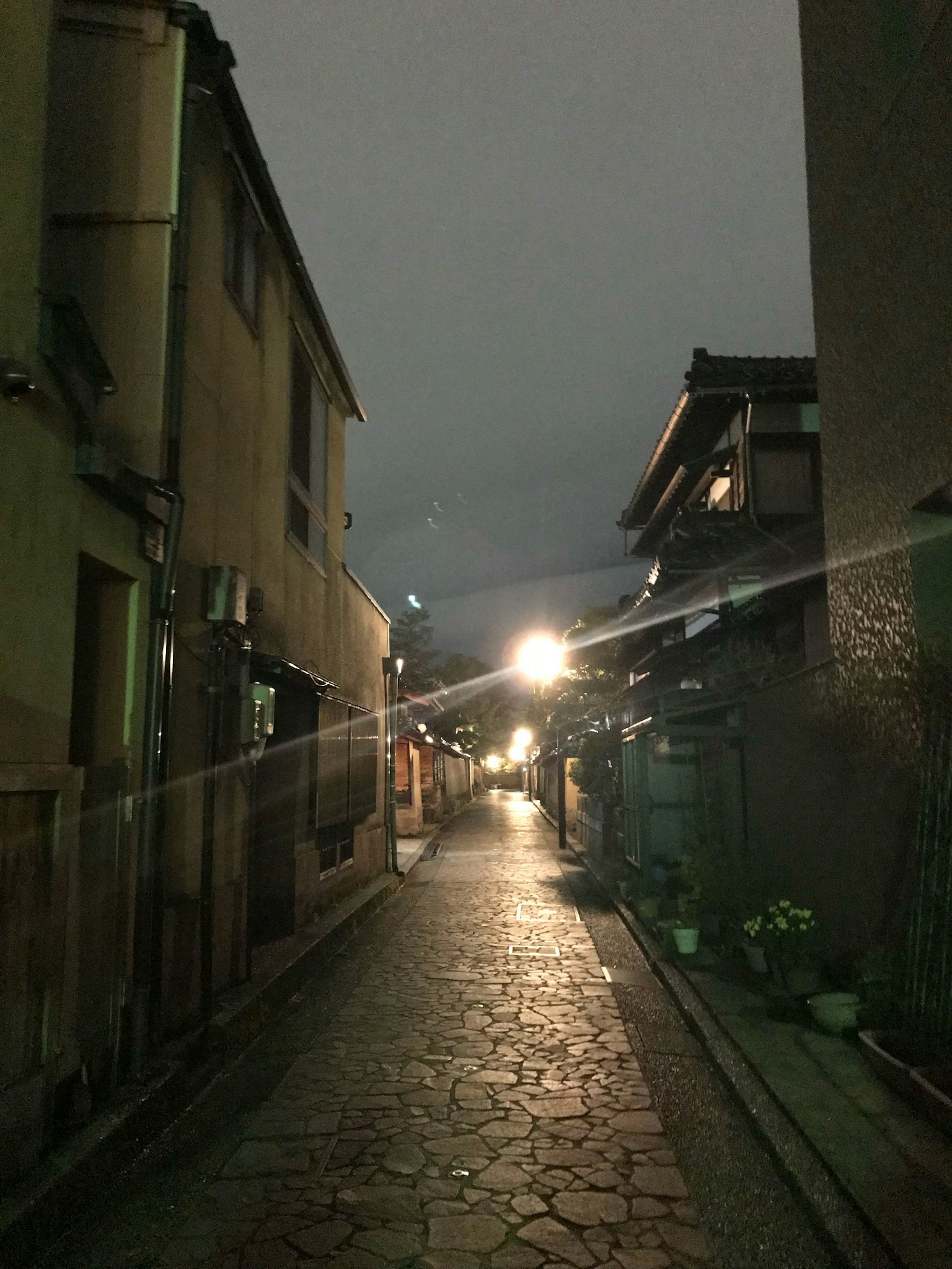 Narrow street lined with old buildings and streetlights at night