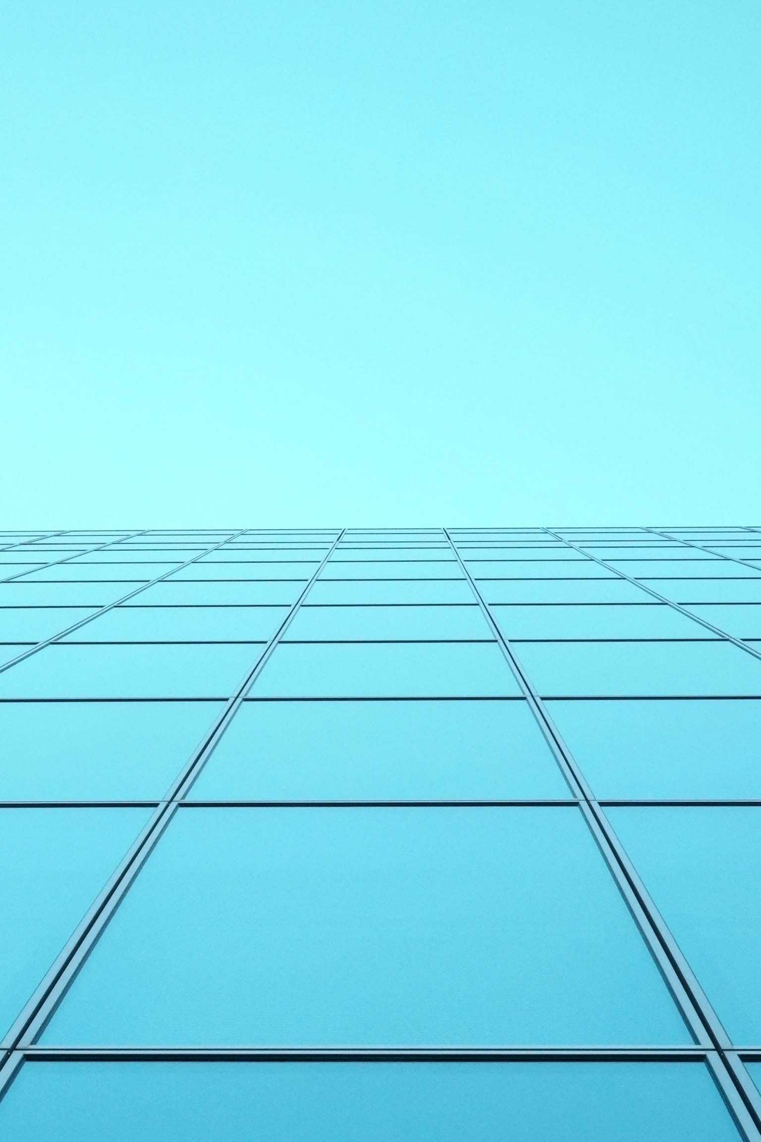 Glasfassade eines Gebäudes vor einem blauen Himmel mit einem Fenstergridschema