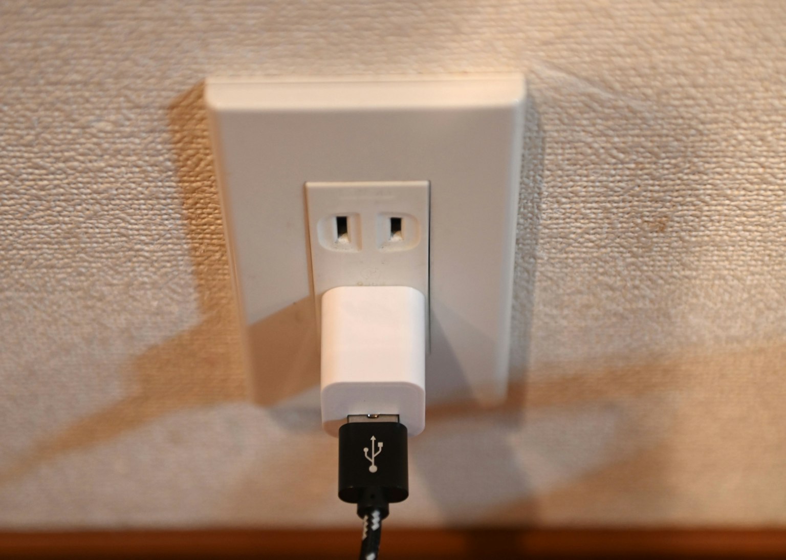 Pengisi daya USB yang terpasang di soket dinding putih
