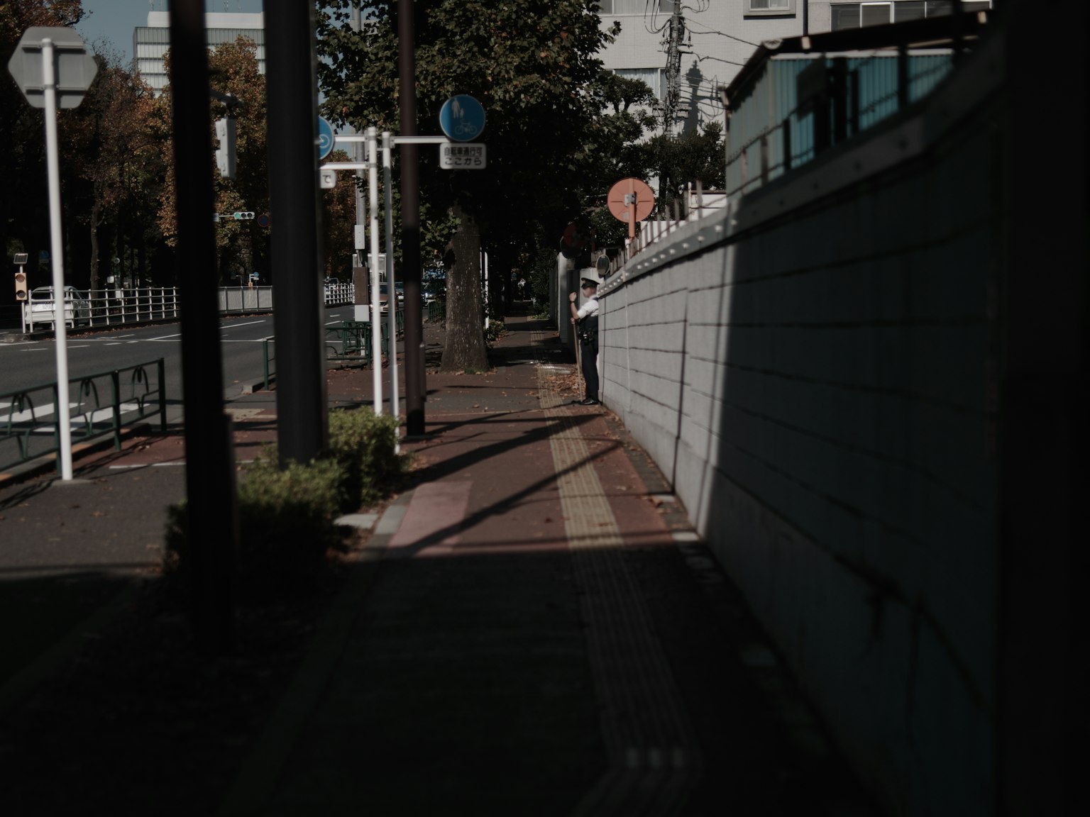 Une silhouette ombragée debout sur un trottoir faiblement éclairé avec des éléments de rue