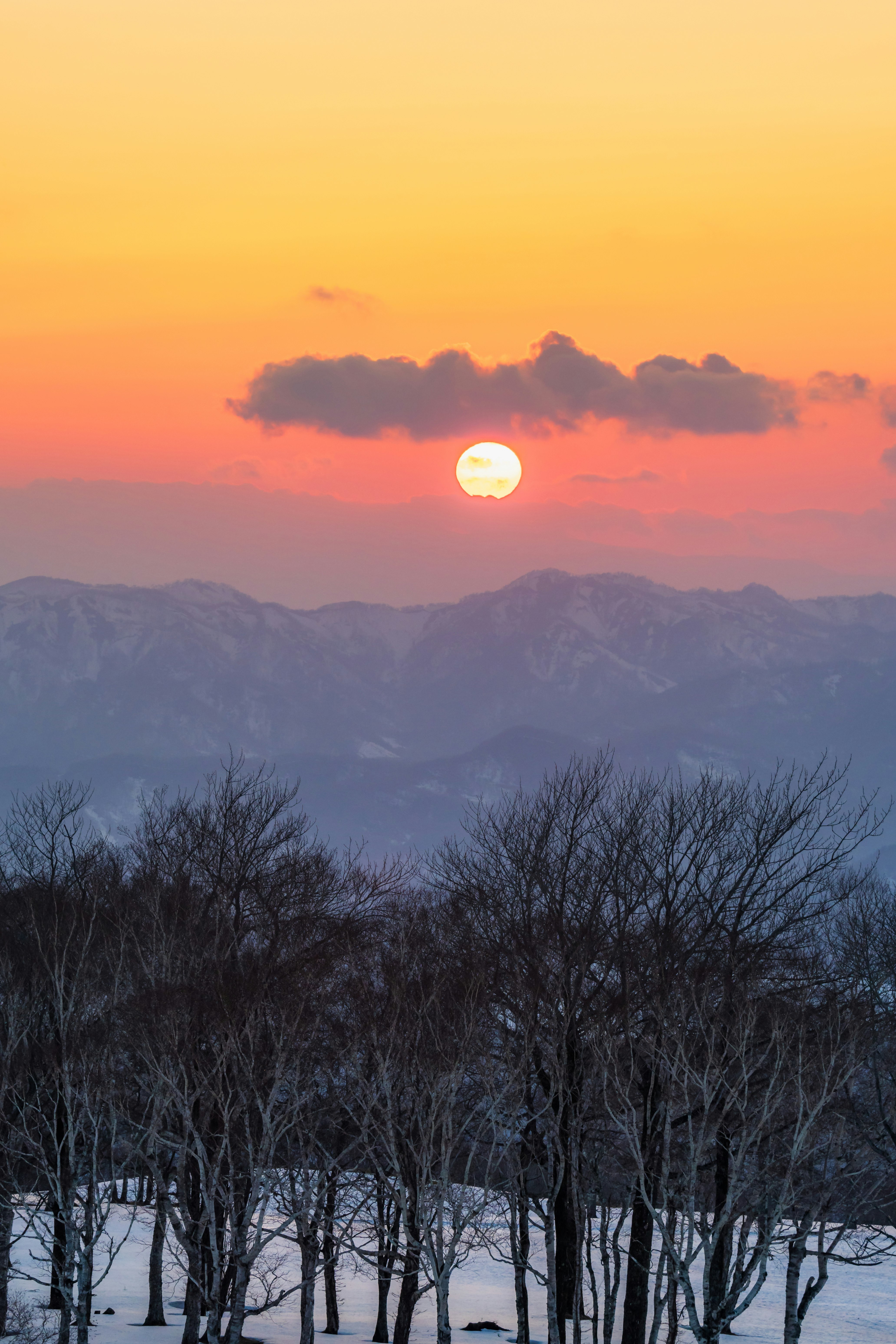 雪の残る山に沈む夕日
