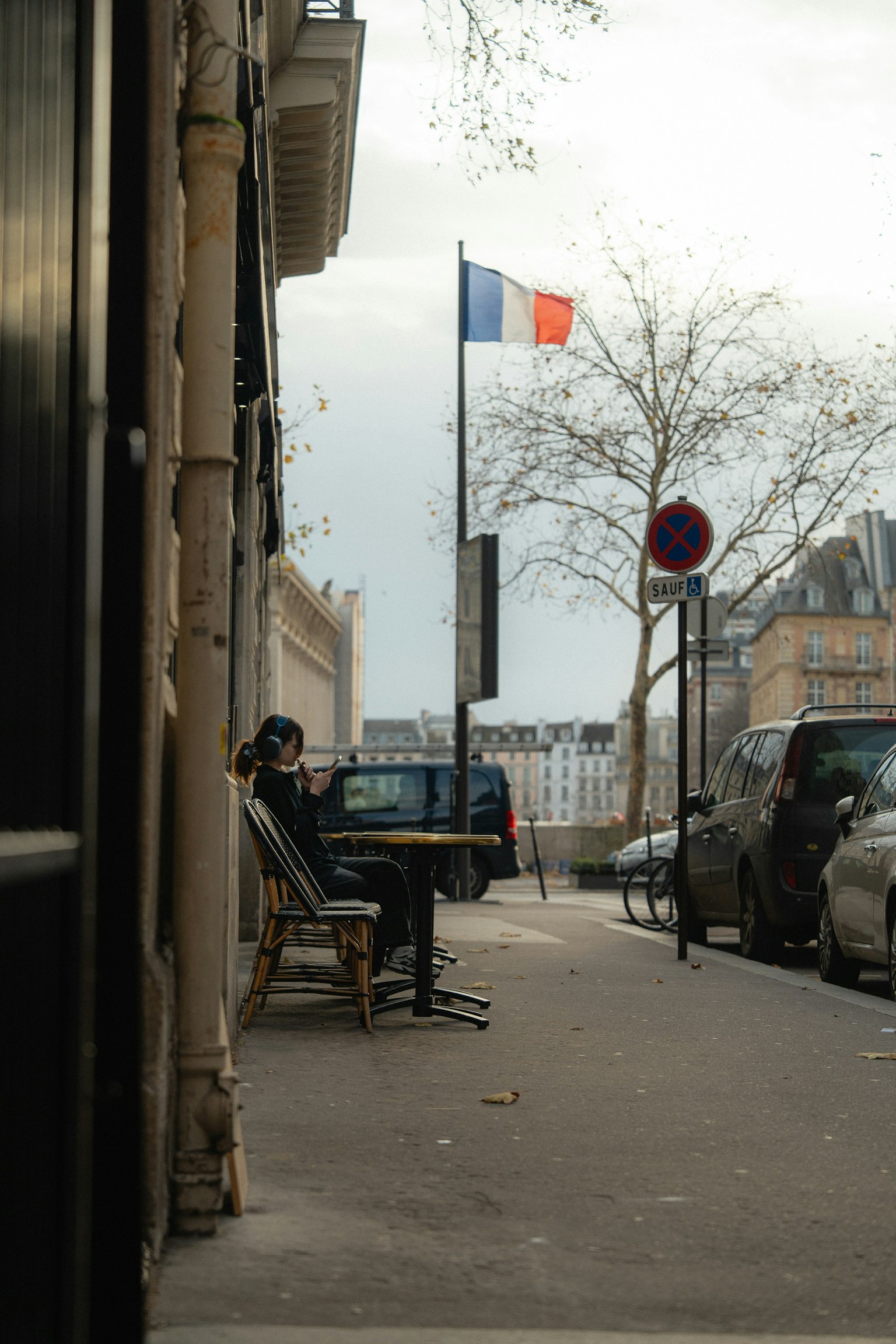 Một người ngồi ở góc phố ở Paris với cờ Pháp