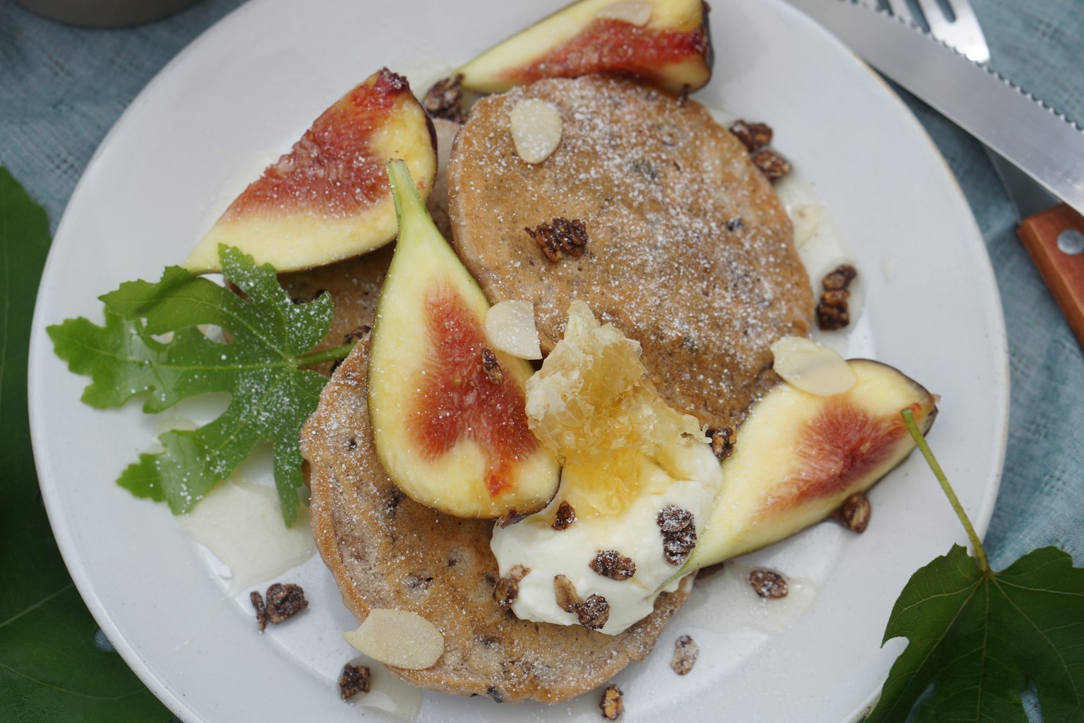Pancake disajikan dengan irisan buah ara segar dan dihiasi kacang