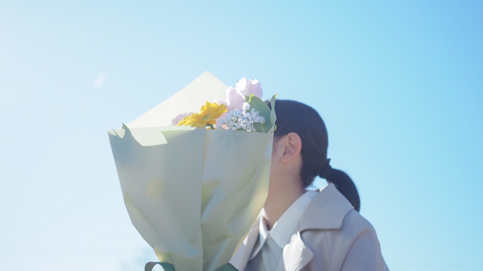Donna che tiene un mazzo di fiori sotto un cielo blu