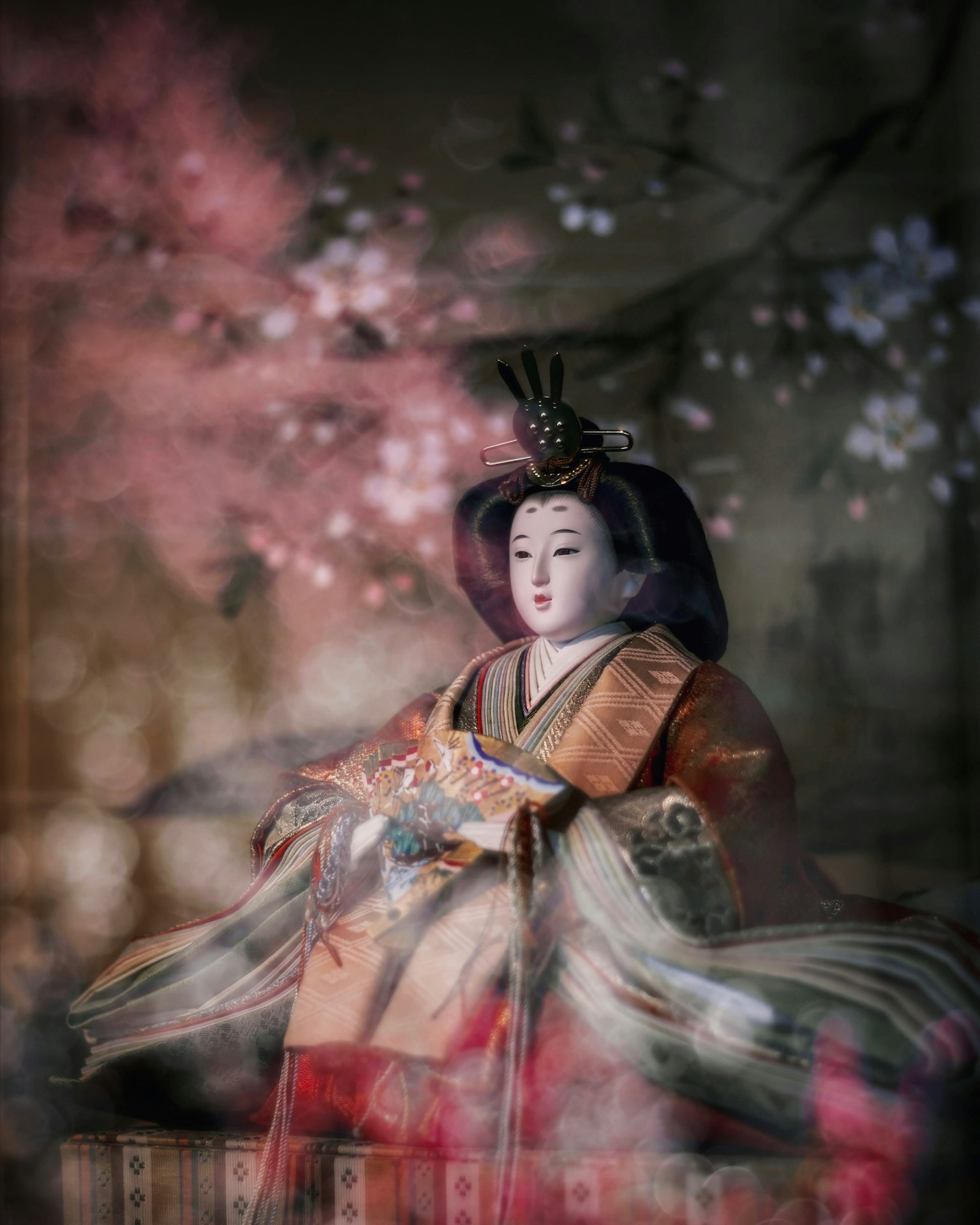 一只穿着和服的美丽娃娃坐在樱花背景前