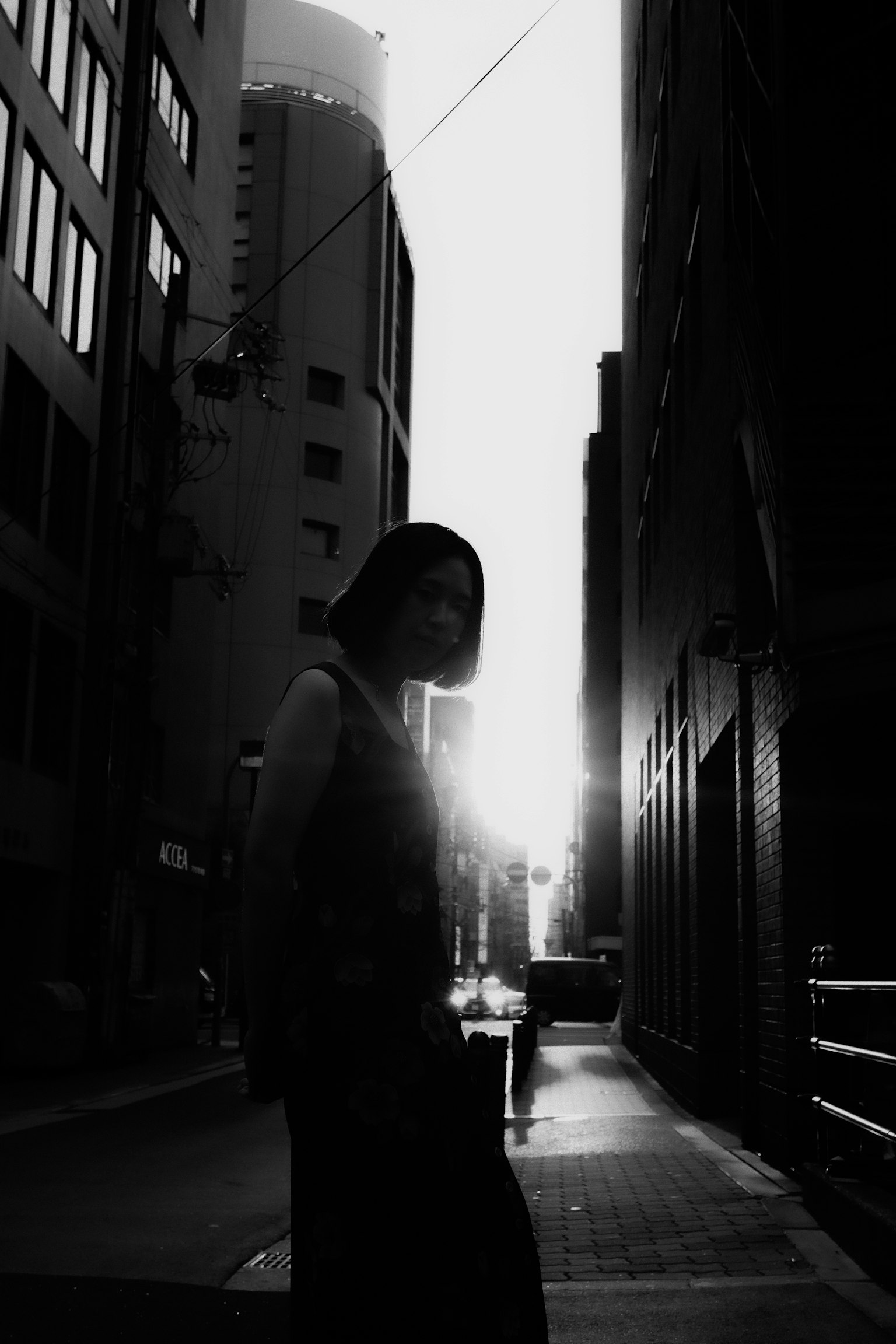 Silhouette di una donna in un vicolo buio con il tramonto sullo sfondo