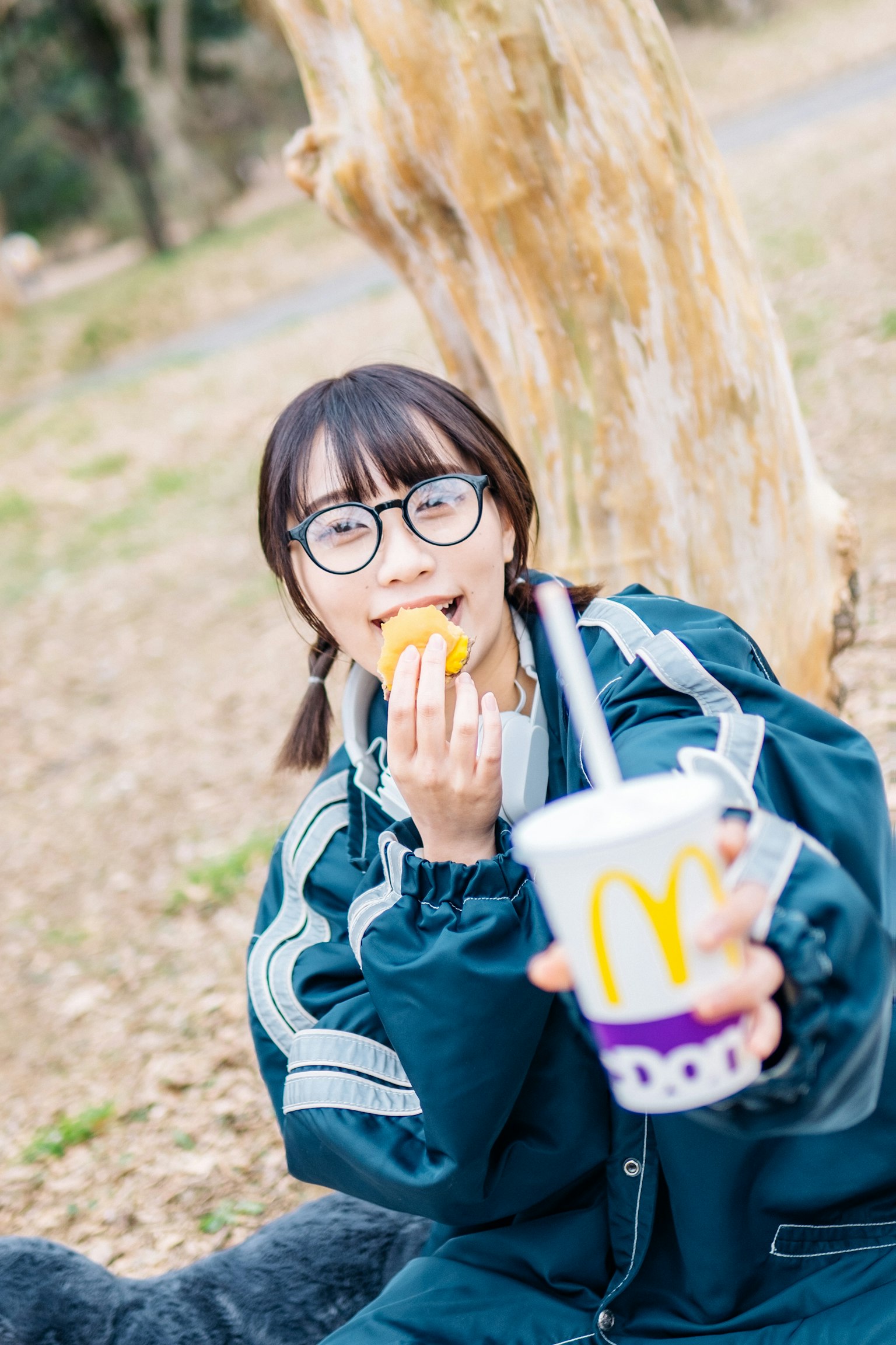 안경을 쓴 여성이 맥도날드 음료를 들고 간식을 먹고 있는 모습
