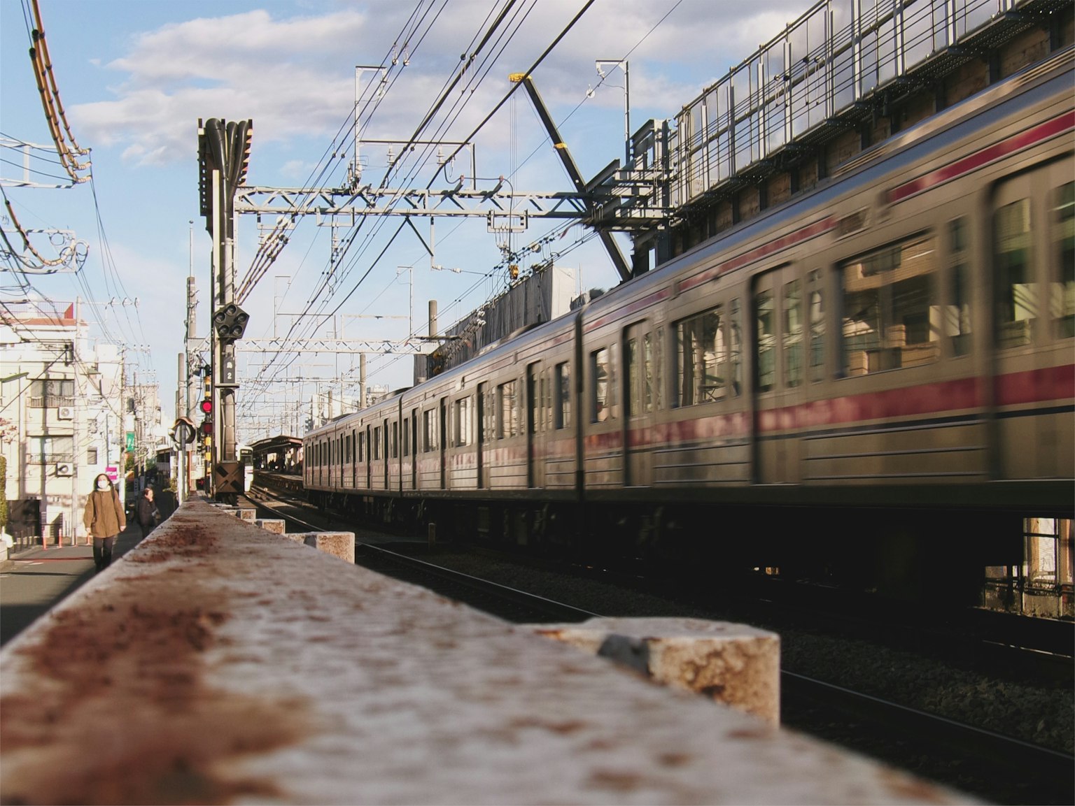 Un treno in movimento su un binario di stazione con cielo azzurro