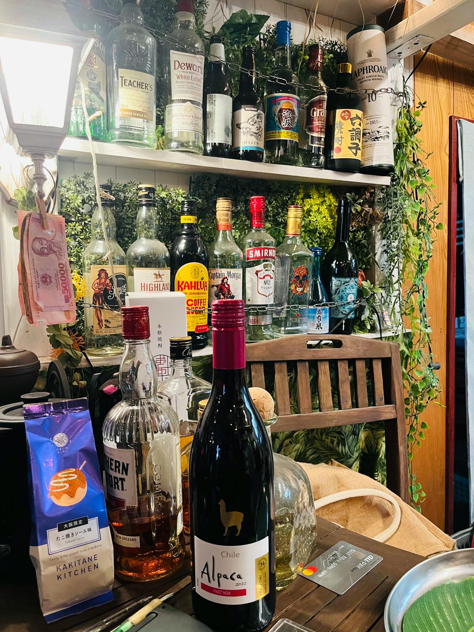 Un accogliente bancone bar con diverse bottiglie di alcol e piante decorative